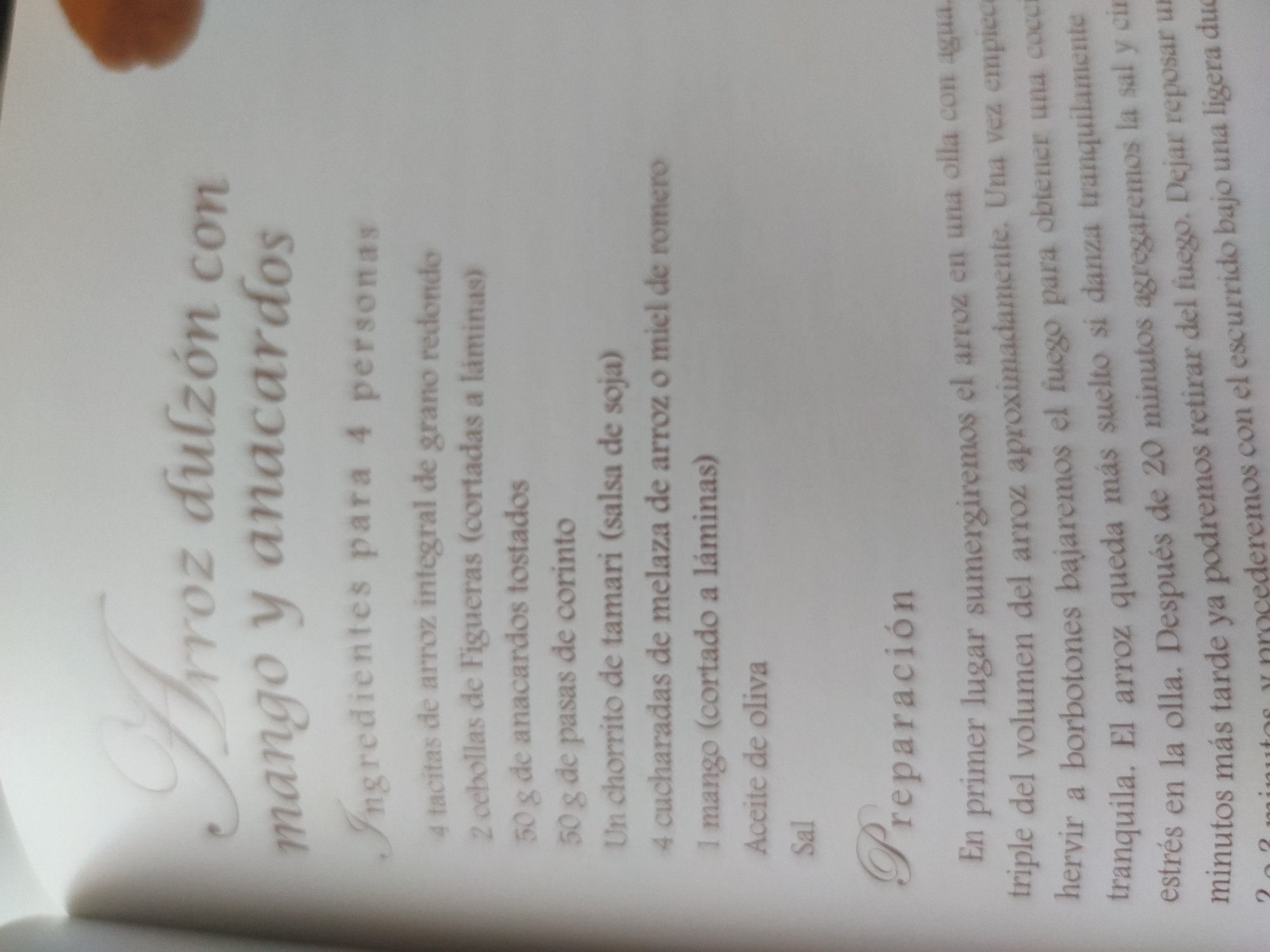 The image shows a page from a recipe book. The title of the recipe is "Arroz dulzón con mango y anacardos" (Sweet rice with mango and cashews). Below the title are the ingredients for 4 people: 4 small cups of round grain integral rice, 2 Figueras onions (cut into slices), 50 g of toasted cashews, 50 g of currants, A dash of tamari (soy sauce), 4 tablespoons of rice molasses or rosemary honey, 1 mango (cut into slices), Olive oil, and Salt. Below the ingredients is the preparation section, which describes how to cook the recipe.