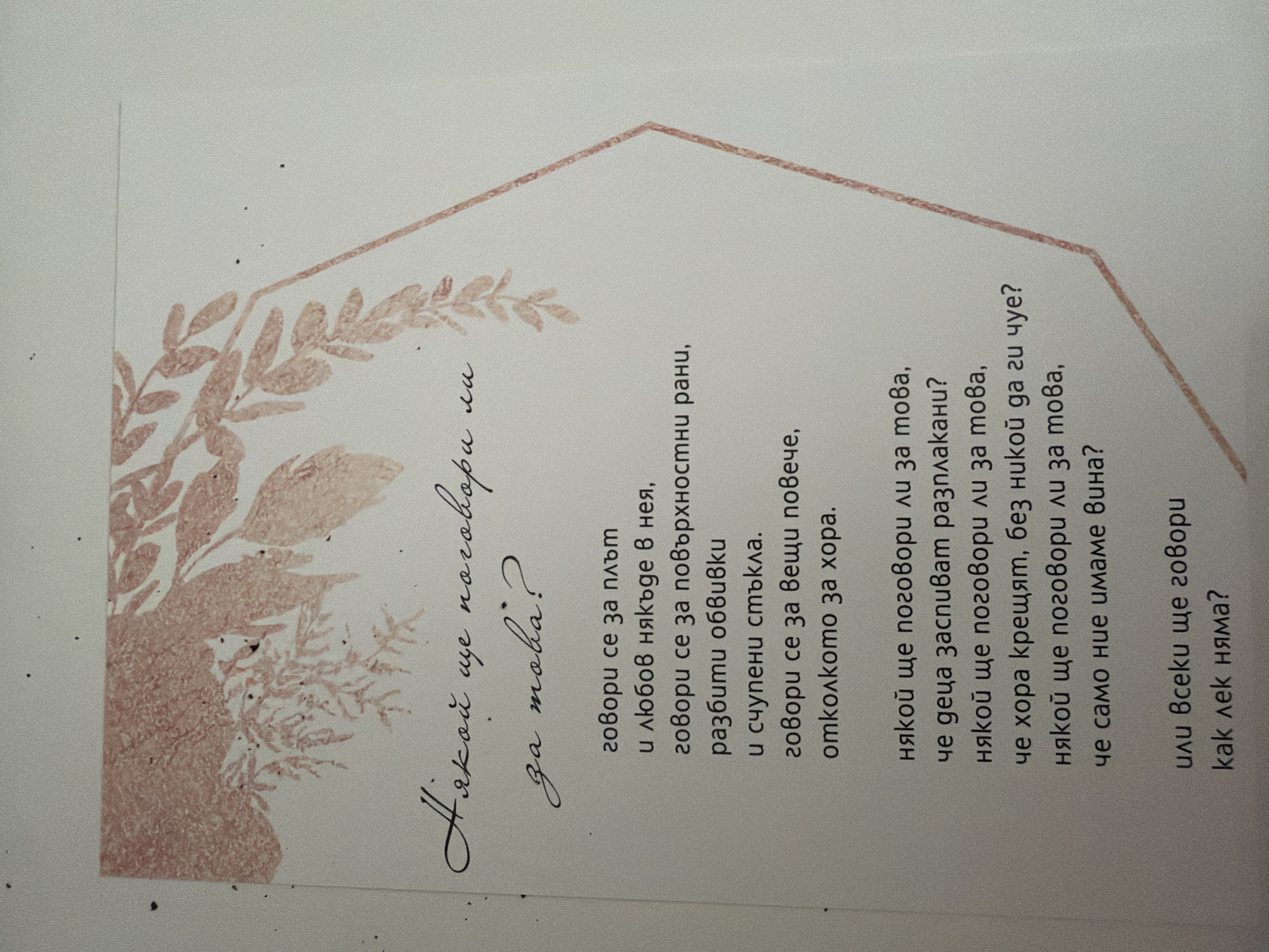 The image is a close-up of a piece of paper with text and decorative elements. The paper has a light, off-white background. In the upper left corner, there is a faded pink floral or leaf-like illustration. The text is handwritten in black ink, with some parts in a more ornate script at the top and the rest in a clearer, blockier font below. The ornate script at the top reads, "Някой ще поговори ли за това?" which translates to "Will someone talk about this?". The block text below it contains several lines of verse, followed by another question. There are also some faint, scattered dark specks on the paper. The image does not contain any information that would allow for the identification of a location in Pazardzhik, Bulgaria.