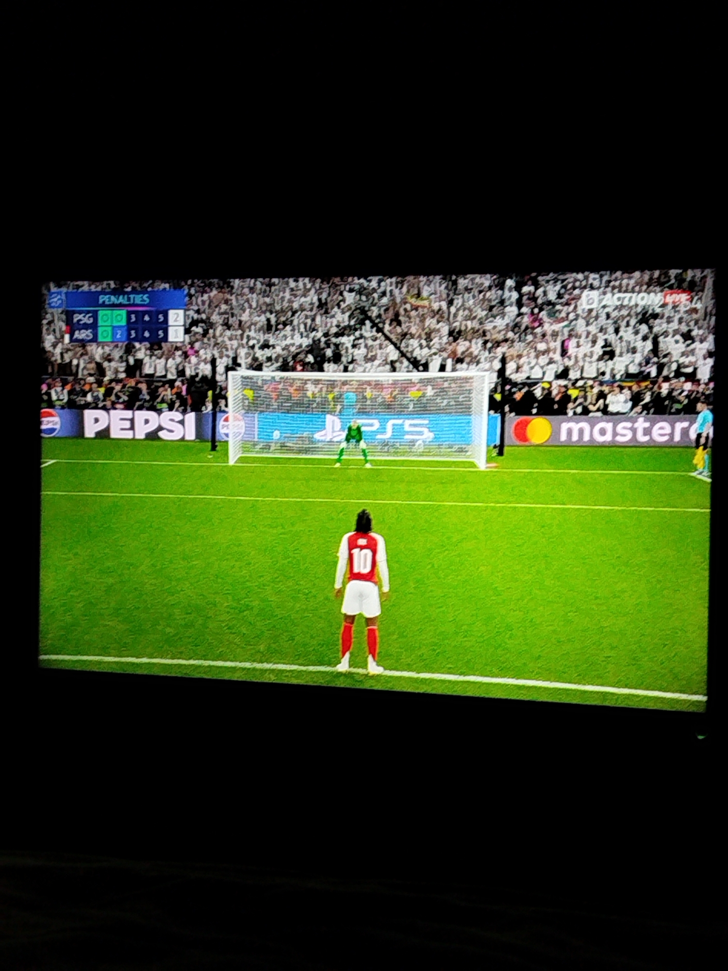 The image depicts a penalty shootout during a soccer match. The score is PSG 3-2 ARS in the penalty shootout. A player wearing jersey number 10 and red and white uniform stands near the penalty spot. The goalkeeper is positioned in front of the goal. The background shows spectators and advertising for Pepsi and Mastercard. The location is not Varna, Bulgaria.