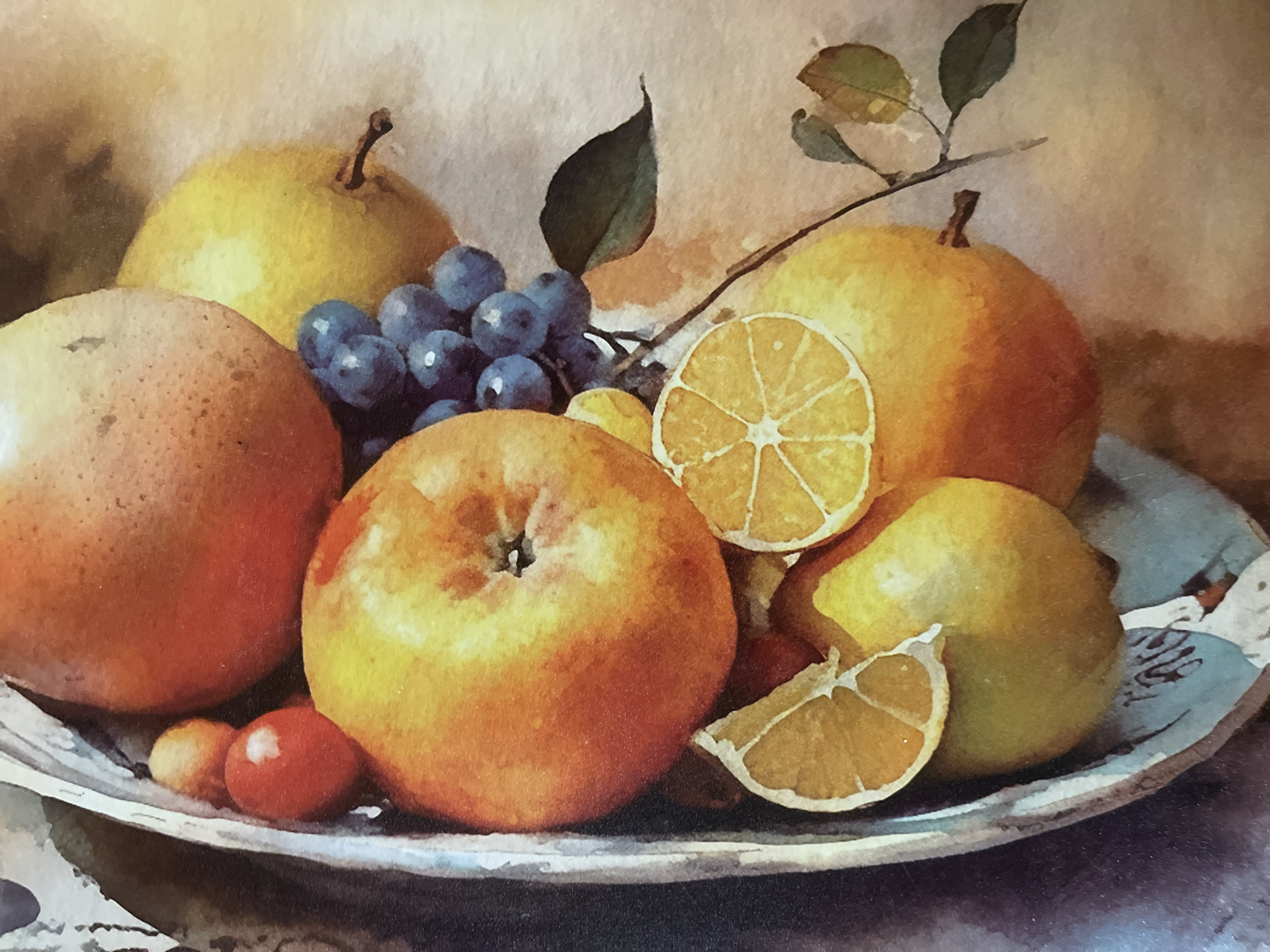This is a still life painting of a fruit bowl. The bowl appears to be made of a light-colored, textured material, possibly ceramic or wood, and is filled with a variety of fruits. Prominently featured are a large red-orange apple, a cluster of dark blue grapes, several yellow pears, a grapefruit or orange, and slices of lemon. Small red berries, possibly cherries or cranberries, are also visible at the top left of the bowl. The fruits are arranged in a loose, naturalistic manner. The background is a soft, diffused warm tone, suggesting a studio setting or an indoor environment. There is no indication of a location in Minsk, Belarus, or any people.