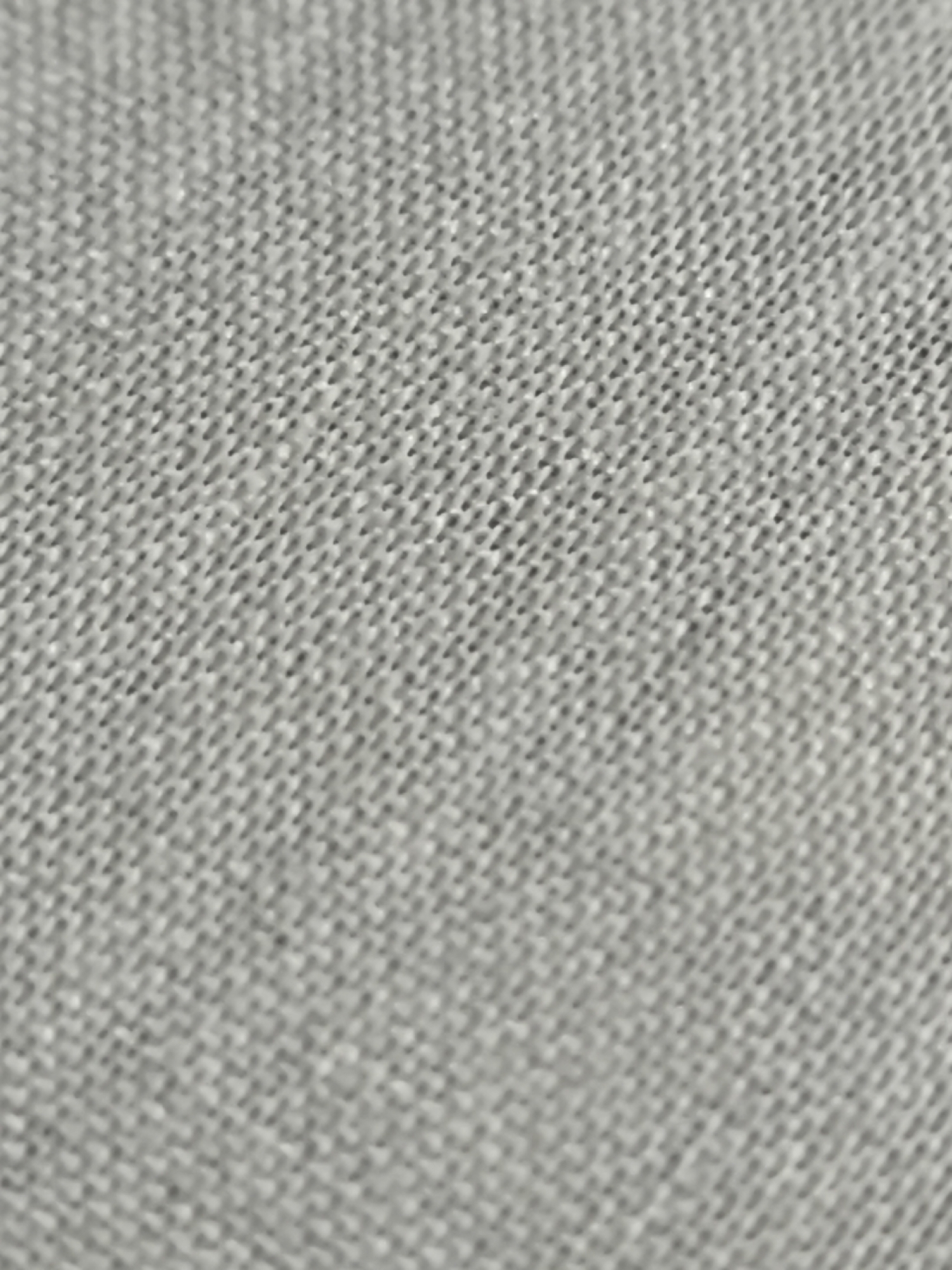 The image is a close-up, abstract shot of a light grey, woven fabric. The texture of the fabric is clearly visible, showing a pattern of interlaced threads. There are no discernible objects, people, or environmental features present in the image, nor is there any indication of the city of Cilegon, Indonesia. The image is purely a textural study of fabric.