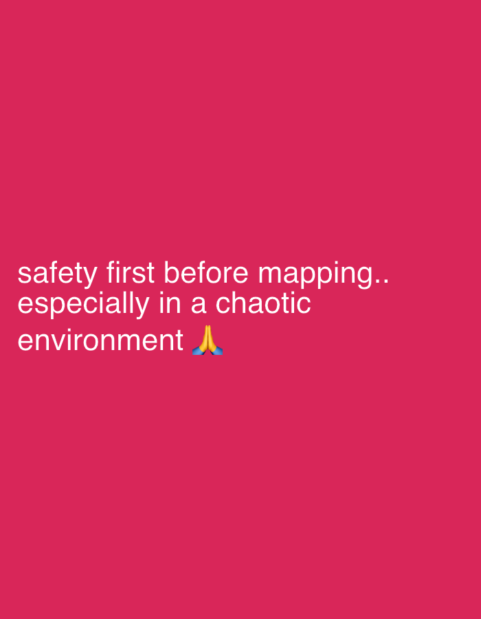 The image features white text displayed against a solid reddish-pink background. The text reads: "safety first before mapping.. especially in a chaotic environment". Immediately following the text, there is a blue and yellow praying hands emoji (🙏). The composition is simple and graphic, with no visible people or specific objects other than the text and emoji. The background is uniformly colored, suggesting a digital graphic rather than a photograph of a physical scene. The message emphasizes the paramount importance of safety, particularly when engaging in "mapping" activities within a disordered or challenging setting. The emoji conveys a tone of reverence, appeal, or acknowledgment regarding the safety imperative. No specific location cues or environmental details are visible in the image to directly link it to Onitsha, Nigeria.