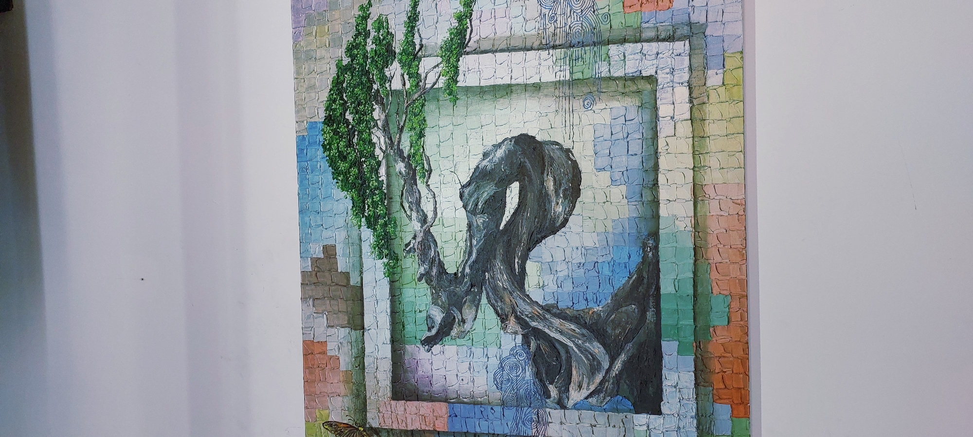 The image shows a painting of a bonsai tree with a textured, mosaic-like background. The bonsai tree is dark and twisted, with a full canopy of green leaves. The background consists of small, square tiles in various pastel colors, creating a vibrant and abstract effect. There is also a hint of a butterfly on the left side of the painting. The painting is hung on a white wall. There is no indication of the city of Curug Sangereng, Indonesia in the image.