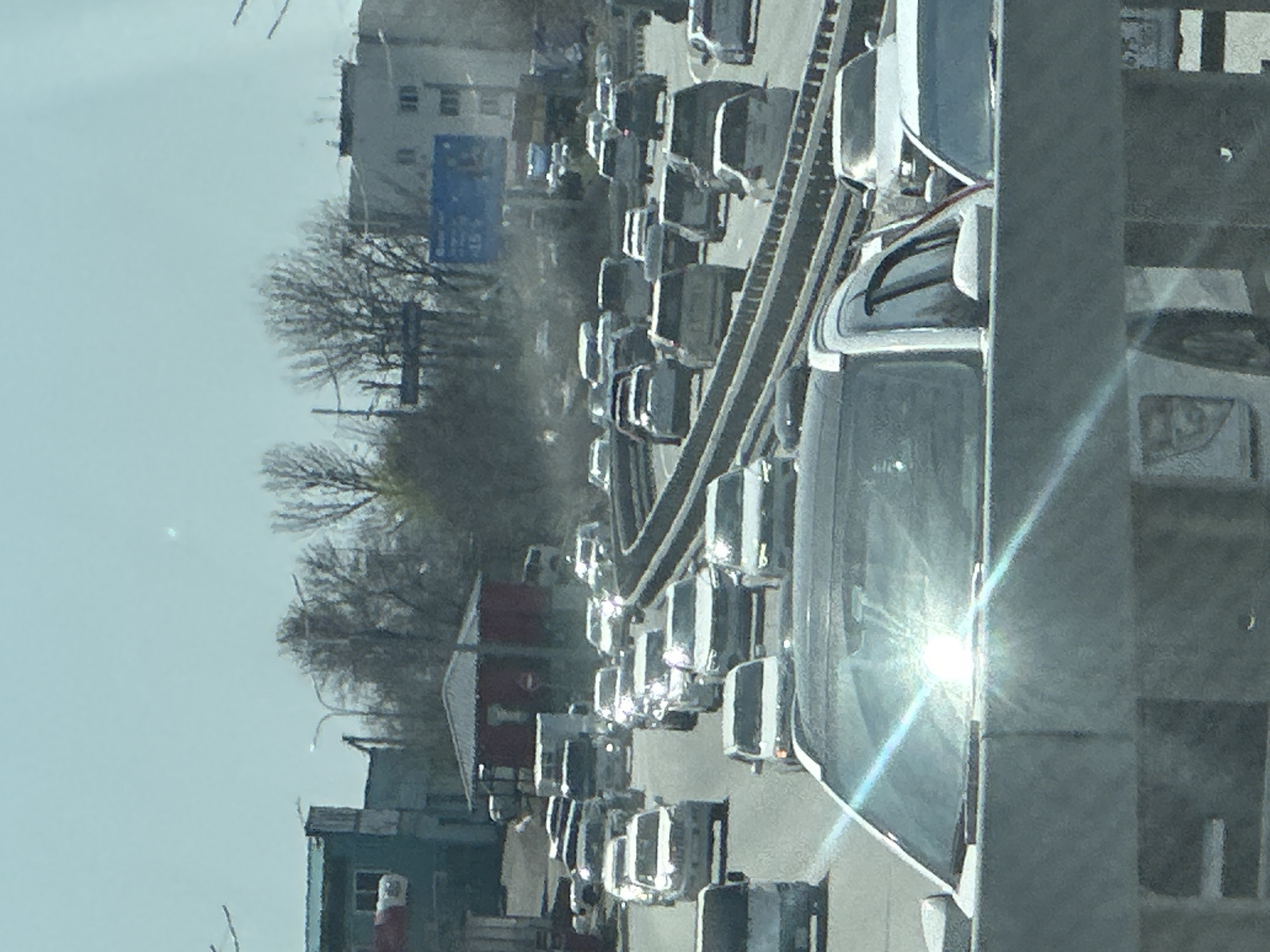 The image shows traffic congestion on a roadway with a building in the background and trees to the side, potentially in an urban area. The exact location within the city is not identifiable.