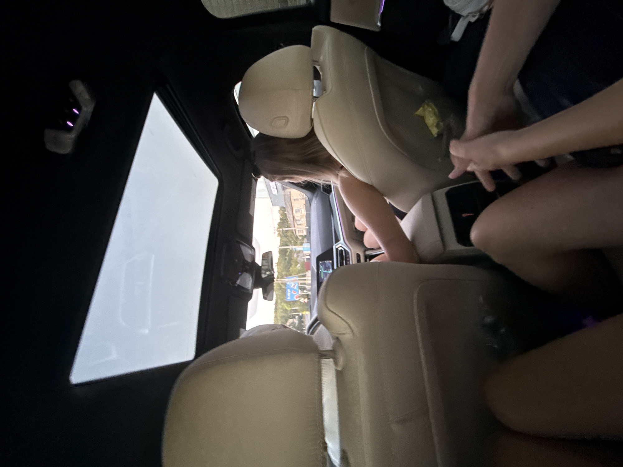 The image shows the interior of a car with a panoramic sunroof. Two individuals are in the front seats, and at least two individuals are in the back seats, with one in the foreground holding hands with someone else. The car appears to be moving on a road with buildings and trees visible outside. The image is taken from the perspective of someone in the back seat. The location is stated to be Fundul Galbenei, Moldova.