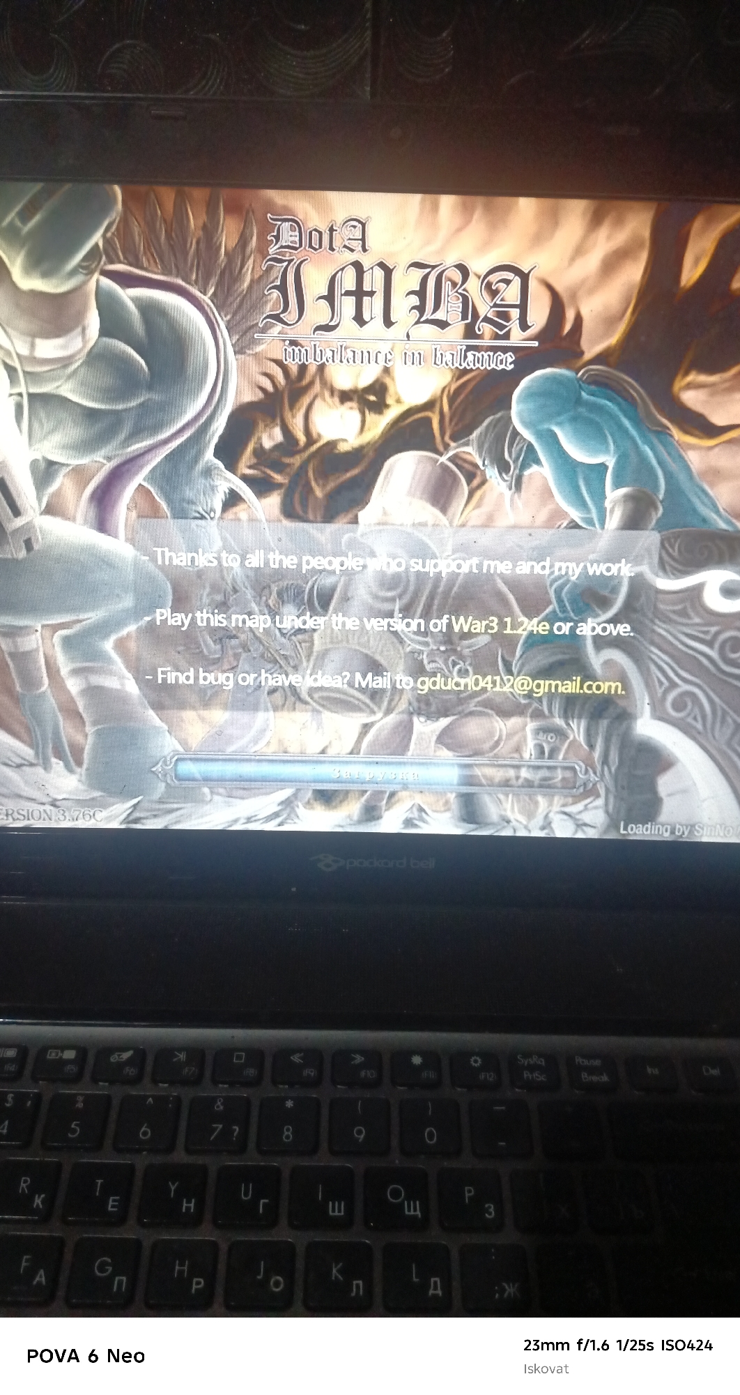 The image shows a computer screen displaying a game title screen for "Dota IMBA" with the subtitle "imbalance in balance." Below the title, there are three lines of text providing information to the player. The first line states, "Thanks to all the people who support me and my work." The second line instructs, "Play this map under the version of War3 1.24e or above." The third line asks, "Find bug or have idea? Mail to gducn0412@gmail.com." At the bottom of the screen, there is a loading bar with Russian text that translates to "Loading." To the left of the loading bar, it says "ERSION 3.76C." To the right, it says "Loading by SinNo." The image also shows a keyboard, which appears to be from a laptop, with a "Packard Bell" logo visible below the screen. The keyboard has both English and Cyrillic characters on the keys. The provided location "Pastki-Peshkurgan, Uzbekistan" is not depicted in the image. The image is a photograph of a computer screen and keyboard.