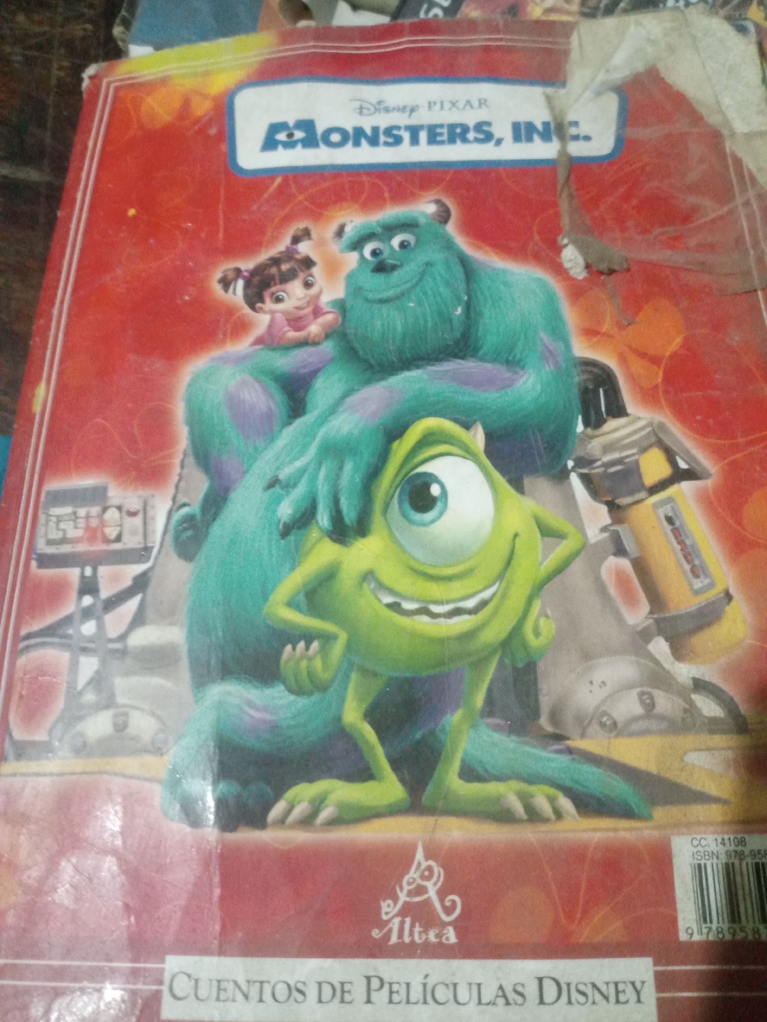The image shows the cover of a "Monsters, Inc." children's book. The characters Sulley and Mike Wazowski are prominently featured, along with a smaller character, Boo, on Sulley's shoulder. The background is a red cover with the Disney Pixar logo and "Monsters, Inc." title. On the lower part of the cover, there is the Altea logo and the text "CUENTOS DE PELÍCULAS DISNEY". The book appears to be in moderate condition with some scuffs and wear visible. This image was taken in Santa Ana, Venezuela.