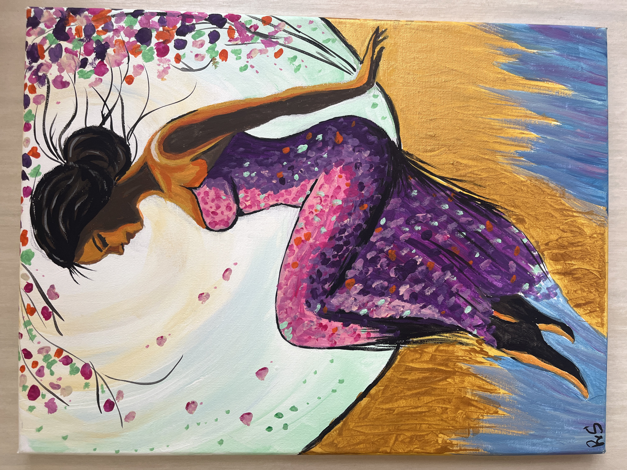 This acrylic painting on canvas features a stylized depiction of a dark-skinned woman in a dynamic, graceful pose, set against an abstract and vibrantly colored background. The woman, with her dark hair pulled into a neat bun, has her eyes closed and head tilted back slightly, conveying a sense of peace, surrender, or intense feeling. Her bare arms are outstretched, and she wears a long, flowing dress primarily in shades of purple and pink, adorned with scattered colorful speckles in orange, light green, and various pink and purple tones, giving it a rich, textured appearance. Her skin is rendered in warm, golden-brown hues.
The background is distinctly segmented. To the upper left, abstract black branch-like elements extend upwards, bearing clusters of small, colorful shapes in pink, orange, purple, and green, suggestive of blossoms or leaves. A large, curved, light-colored section in the center-left features soft washes of cream, light blue, and light green, with scattered small pink and green petal-like shapes, forming a radiant aura or portal around the woman. The right side of the canvas is dominated by a shimmering metallic gold background, heavily textured with visible brushstrokes, which transitions into a vibrant area of blues and purples on the far right.
The overall composition suggests a moment of serene movement, perhaps dancing, floating, or soaring, within a symbolic or dreamlike environment. The artist's signature, "RS," is visible vertically in the bottom right corner of the painting.
