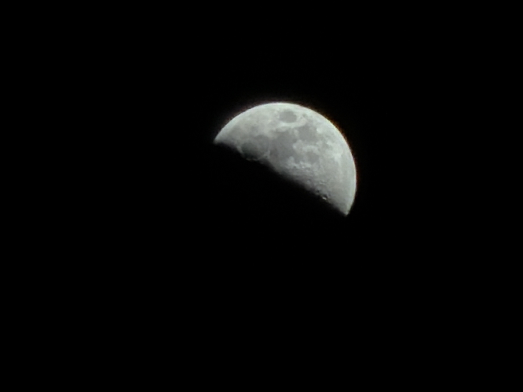 The image shows a half moon in the night sky. The background is entirely black. There is no information in the image to indicate a location in Izhevsk, Russia or to describe any people, subjects, objects, actions, or interactions beyond the presence of the moon itself.