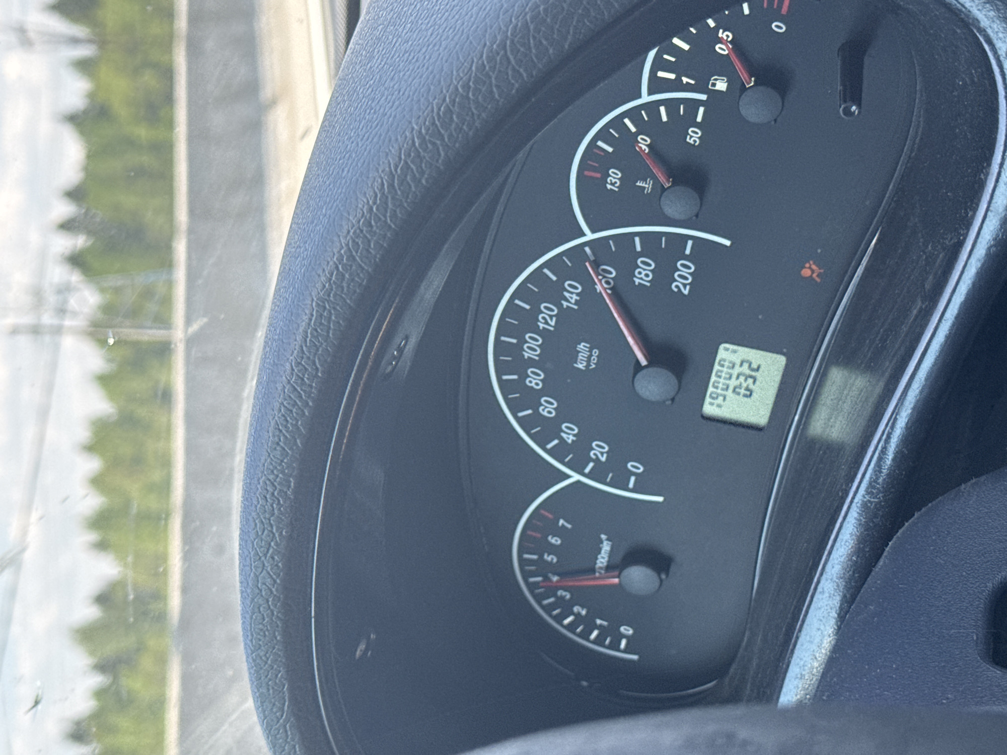 The image shows the dashboard of a vehicle, with a focus on the speedometer indicating a speed around 150 km/h. Other gauges visible include the fuel level, temperature gauge, and tachometer, which shows approximately 3000 RPM. The odometer reads 190001. The airbag warning light is on. Through the windshield, there's a blurred view of what appears to be a highway or road with roadside vegetation and power lines visible. Without further information, the location within Perm, Russia, cannot be conclusively determined.
