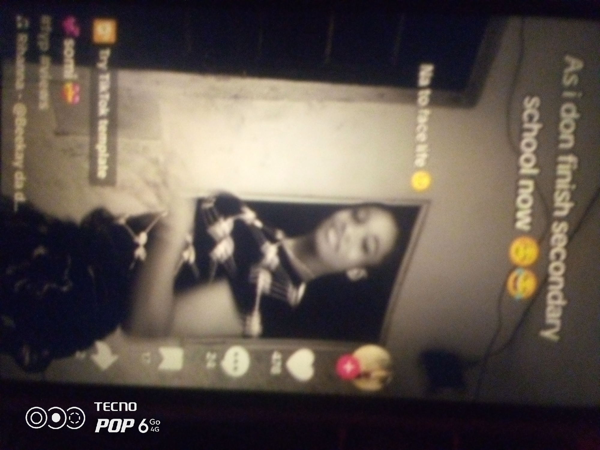 The image is a low-resolution, blurry, black and white photograph of a person looking out of a window, likely taken from a mobile phone screen. The person appears to be a young female with dark hair, wearing a patterned top. Text overlays suggest a social media platform, possibly TikTok, with phrases like "Try TikTok template," "No to face life," and "As i don finish school now." The bottom of the image displays the "TECNO POP 6 4G" logo. The scene's location in Howayi, Nigeria, is not discernible from the visual information provided.