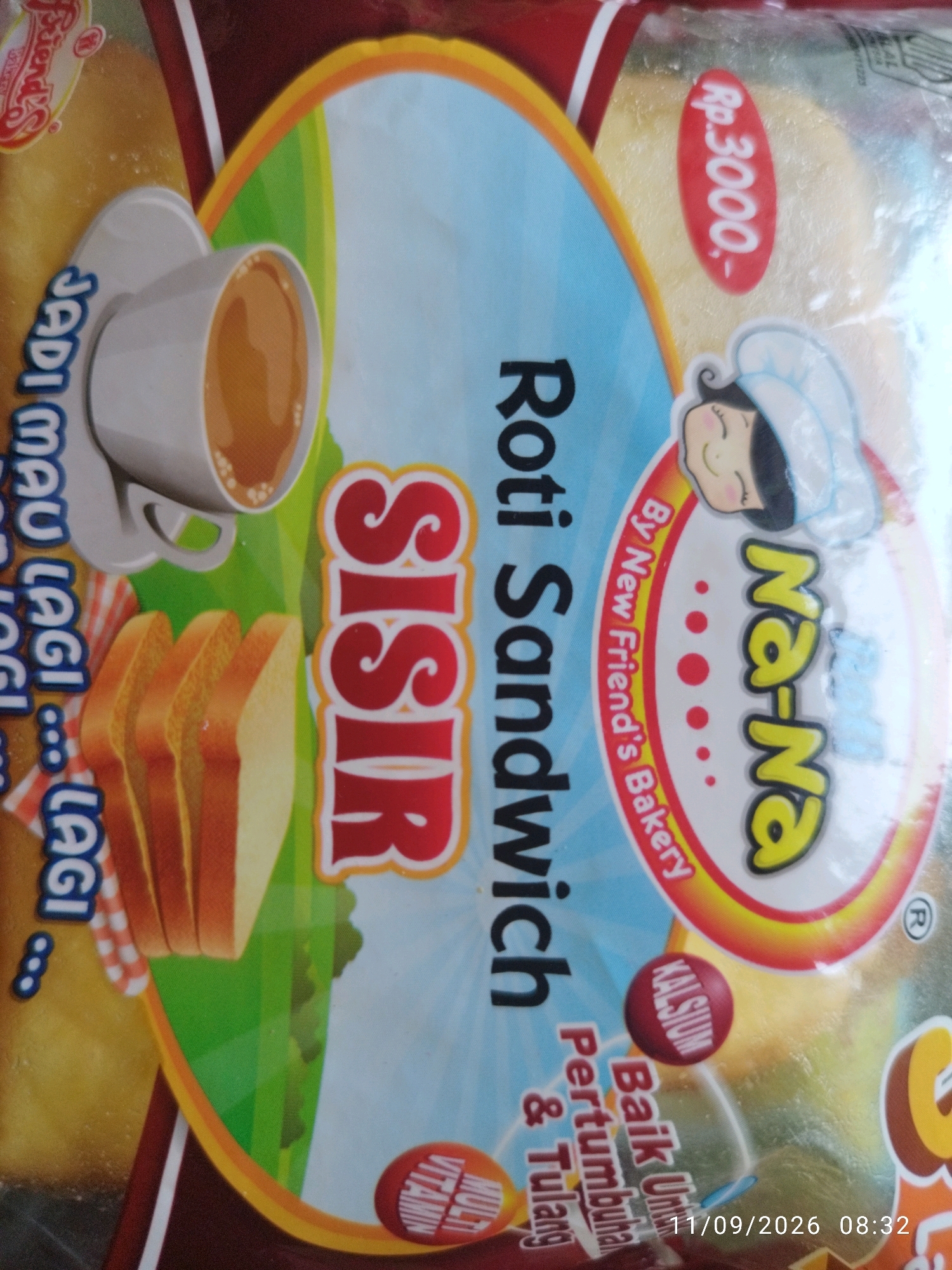 This image is a close-up shot of a product package, likely for bread or a similar baked good. The packaging features vibrant colors and cartoonish graphics, including a steaming cup of coffee and sliced bread. Prominently displayed are the words "Roti Sandwich" and "SISIR" in large, bold letters. There's also a character of a child wearing a chef's hat, and branding that includes "Na-Na" and "By New Friend's Bakery." A red oval with "Rp. 3000,-" indicates a price. Smaller text mentions "Kalsium" and "Baik Untuk Pertumbuhan & Tulang," suggesting health benefits. The bottom right corner displays a timestamp: "11/09/2026 08:32". The context of Mojokerto, Indonesia, is not visually present in the image itself, but the use of Indonesian language on the packaging suggests a connection to that region.