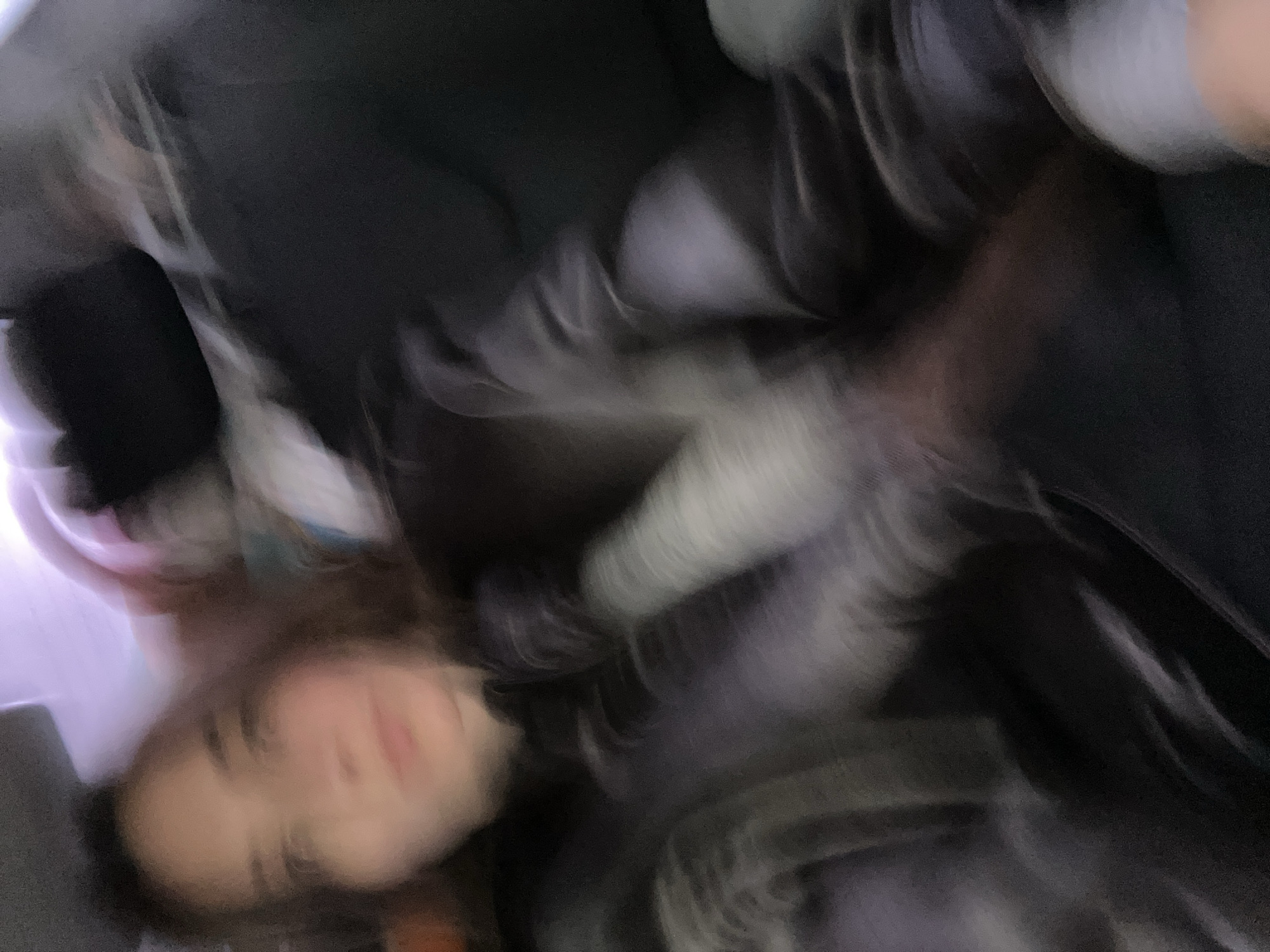 The image shows a blurry, low-angle selfie of a person with light skin and brown hair. The person is wearing a dark jacket or coat. The background is indistinct, consisting of dark and light areas with blurred shapes. The image does not contain enough information to determine the location, much less identify it as Moscow, Russia.
