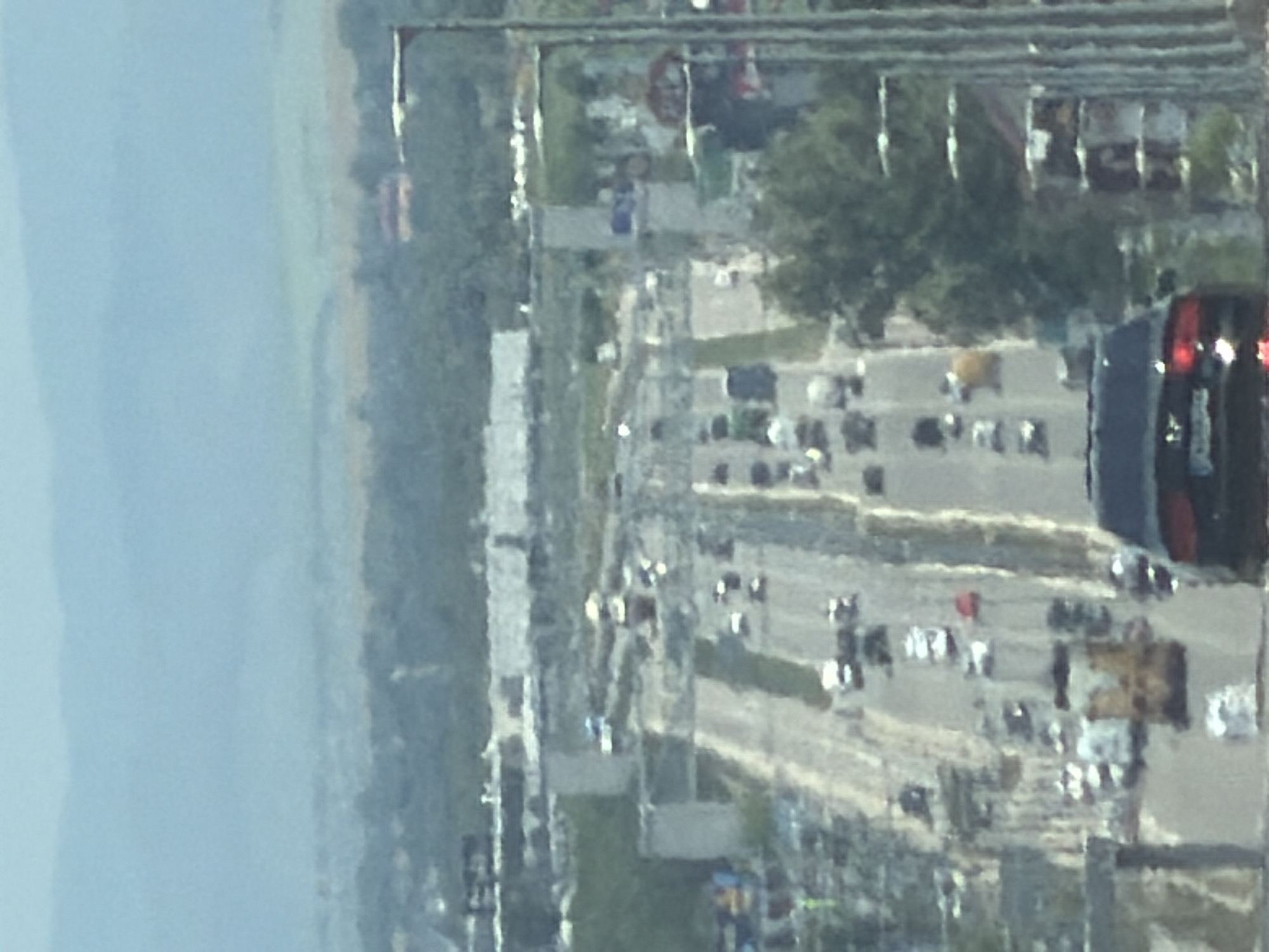 The image shows a highway in Sofia, Bulgaria, with multiple lanes of traffic. Several cars are visible on the road, including a black sedan in the foreground. Construction appears to be ongoing, with scaffolding and unfinished structures along the highway. In the background, rolling hills and a hazy sky can be seen. The scene is an aerial view, suggesting the photo was taken from an elevated position, possibly a drone or a tall building.