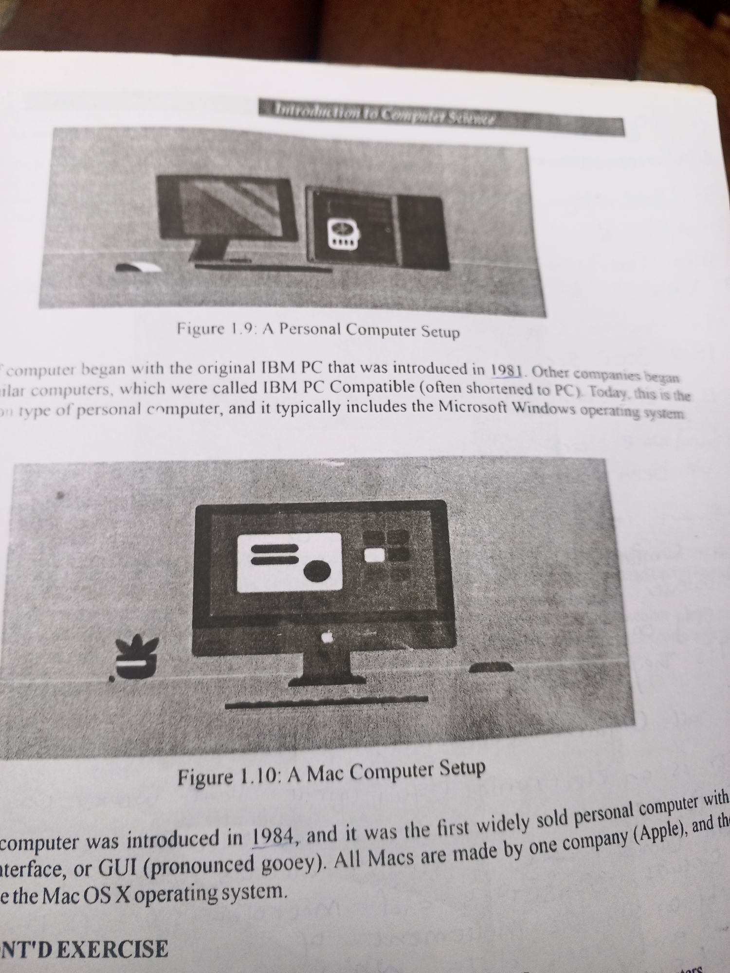 This media file is a photograph of an open textbook page, focusing on two black and white illustrations of early personal computers and the accompanying text. The page appears to be from a book about computer science, as indicated by the visible text "Introduction to Computer Science" at the top.
The first illustration, labeled "Figure 1.9: A Personal Computer Setup," depicts an IBM PC, characterized by a monitor, a keyboard, and what appears to be a separate processing unit. The text below this figure discusses the introduction of the original IBM PC in 1981 and the concept of IBM PC Compatible computers.
The second illustration, labeled "Figure 1.10: A Mac Computer Setup," shows an early Apple Macintosh computer, featuring a distinctive all-in-one monitor design and a mouse. The text below this figure explains that the Mac computer was introduced in 1984 and highlights its graphical user interface (GUI).
The overall scene is a close-up of a printed page, suggesting it's part of an educational resource. There are no people visible, and the focus is entirely on the static images and text. The lighting is consistent with indoor photography, and no specific time of day, weather, or geographical location cues are evident within the captured frame itself. The context of Jalingo, Nigeria, is external information and not derivable from the image content. The dominant emotion conveyed is informative and educational.