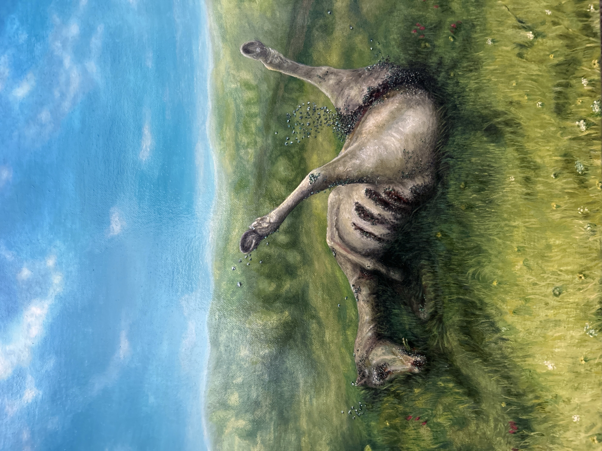 The image is a painting depicting a deceased animal, possibly a horse or cow, lying on its side in a grassy field. The animal's body is in an advanced state of decomposition, with its ribcage clearly visible and areas of flesh missing. Small, dark, glistening specks, resembling insects or maggots, are scattered on and around the carcass, particularly concentrated near the exposed parts of the body.
The scene is set in a vibrant natural landscape under a bright blue sky, which fills the upper portion of the painting. Soft, white clouds are sparsely distributed across the sky. The lower portion of the image is dominated by a lush green field or meadow, characterized by visible brushstrokes that create the texture of grass. Small white and reddish-pink wildflowers are scattered throughout the field. A distant line of green hills or trees forms the horizon where the field meets the sky.
The painting conveys a somber theme of decay and the natural cycle of life and death. It depicts a clear, daytime setting with fair weather. The artistic medium is evident through distinct brushwork on the canvas. There are no specific location markers for Cape Coral, United States of America, visible within the painting. No text is present in the image.
