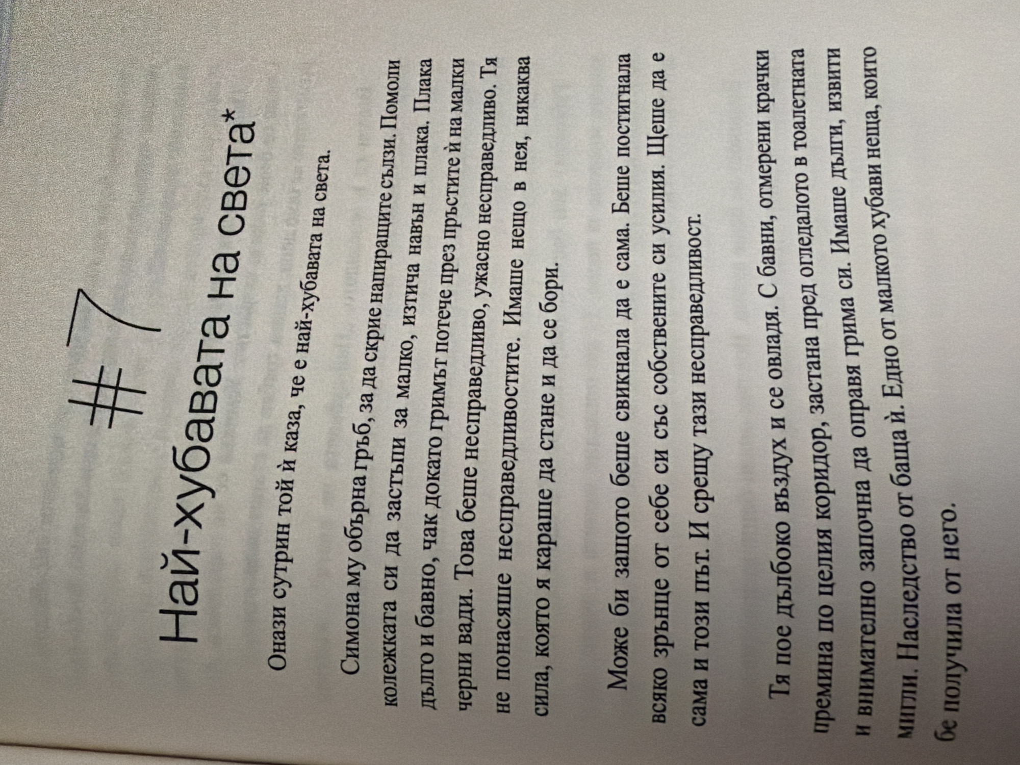 The image is a close-up, slightly angled shot of text printed on a white, textured page, likely from a book. The text is in Bulgarian and appears to be a narrative. At the top, a large numeral "7" is preceded by a hash symbol "#". Below this, a title is prominently displayed: "Най-хубавата на света*" (The Most Beautiful in the World*). The rest of the image is filled with paragraphs of text.
There is no information in the image that would allow for the determination of a location in the city of Pazardzhik, Bulgaria, or any other specific geographical location. The image focuses solely on the printed text.
