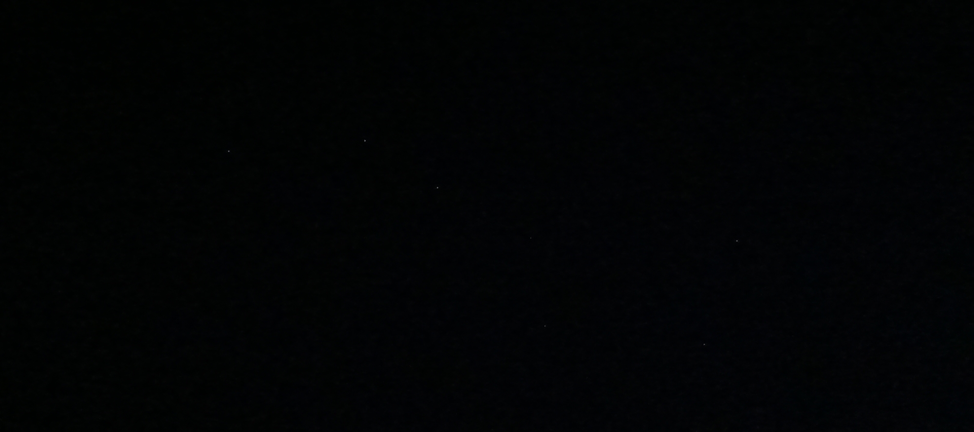 The image is a dark, nearly black photograph with a few small, bright white dots scattered across it. These dots appear to be stars or distant lights, suggesting the photograph was taken at night, likely outdoors. The absence of any discernible features like buildings, landscapes, or people indicates a remote or obscured environment. The location provided, Мерчалово Снт, Russia, suggests a dacha or garden cooperative, which often implies a rural or semi-rural setting outside of a major urban center. The faintness and sparsity of the light sources emphasize the darkness of the surroundings.