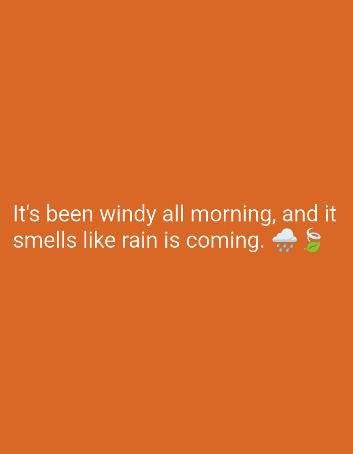 The image shows a close-up of white text on an orange background. The text reads "It's been windy all morning, and it smells like rain is coming." To the right of the text are two emojis: a cloud with raindrops and a swirling leaf, likely representing wind. The image does not contain any information about the city of Manghit, Uzbekistan, or any people or specific environmental details.
