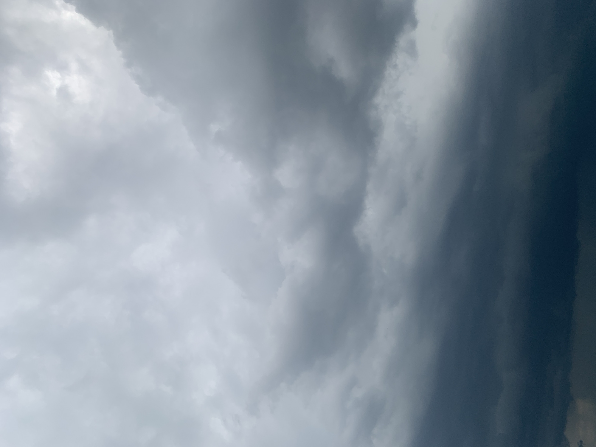 The image shows a sky filled with dark, heavy storm clouds. The clouds are dense and appear to be gathering, with some areas lighter and others very dark, suggesting an approaching storm or overcast weather. The lighting is dim, typical of a cloudy or pre-storm day. The image is a close-up of the sky and does not contain any identifiable landmarks, buildings, or people. Therefore, its specific location within the city of Kolomyia, Ukraine, cannot be determined from the visual information provided. The scene is entirely natural, consisting of atmospheric conditions.