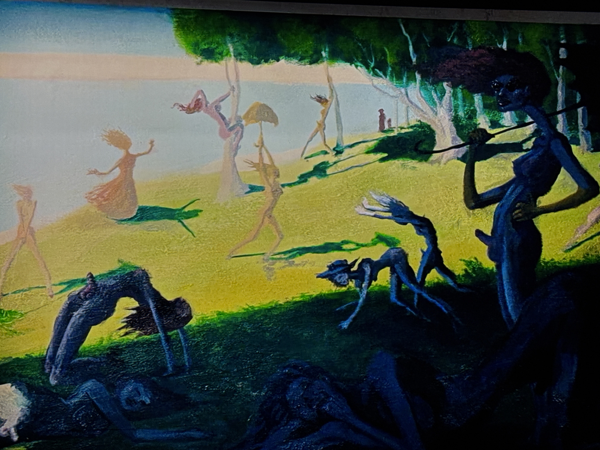 The image depicts a surreal landscape with several figures in varying degrees of activity. In the background, a body of water meets a light sky, suggesting a lake or seaside. Several slender figures, seemingly nude, populate the middle ground, some standing, others interacting with trees, and one carrying a parasol. The foreground is dominated by dark, indigo-colored figures. Some are arched backward, while others are collapsed on the ground. One figure stands upright, holding a long, curved object and sporting an afro-like hairstyle. The environment transitions from a light green, grassy area in the middle ground to a darker, shaded area in the foreground, indicating a forest or shadowed section of the landscape. The location is Unknown, Unknown.