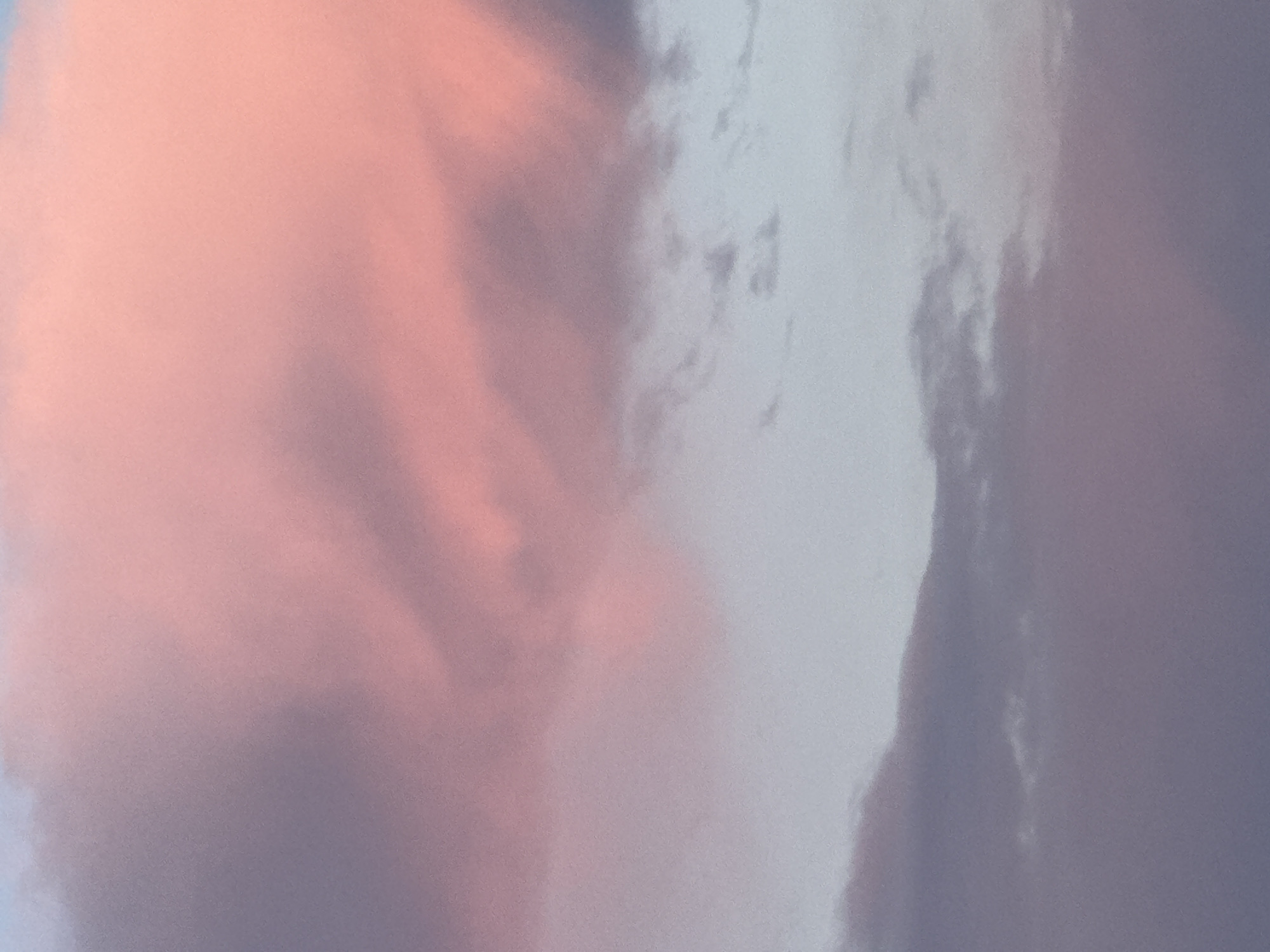 The image shows a close-up of clouds. The clouds are colored with a mix of pink and white hues, suggesting a sunset or sunrise. The location is unknown, since the image does not offer information to identify the location of Новая Разводная, Russia.