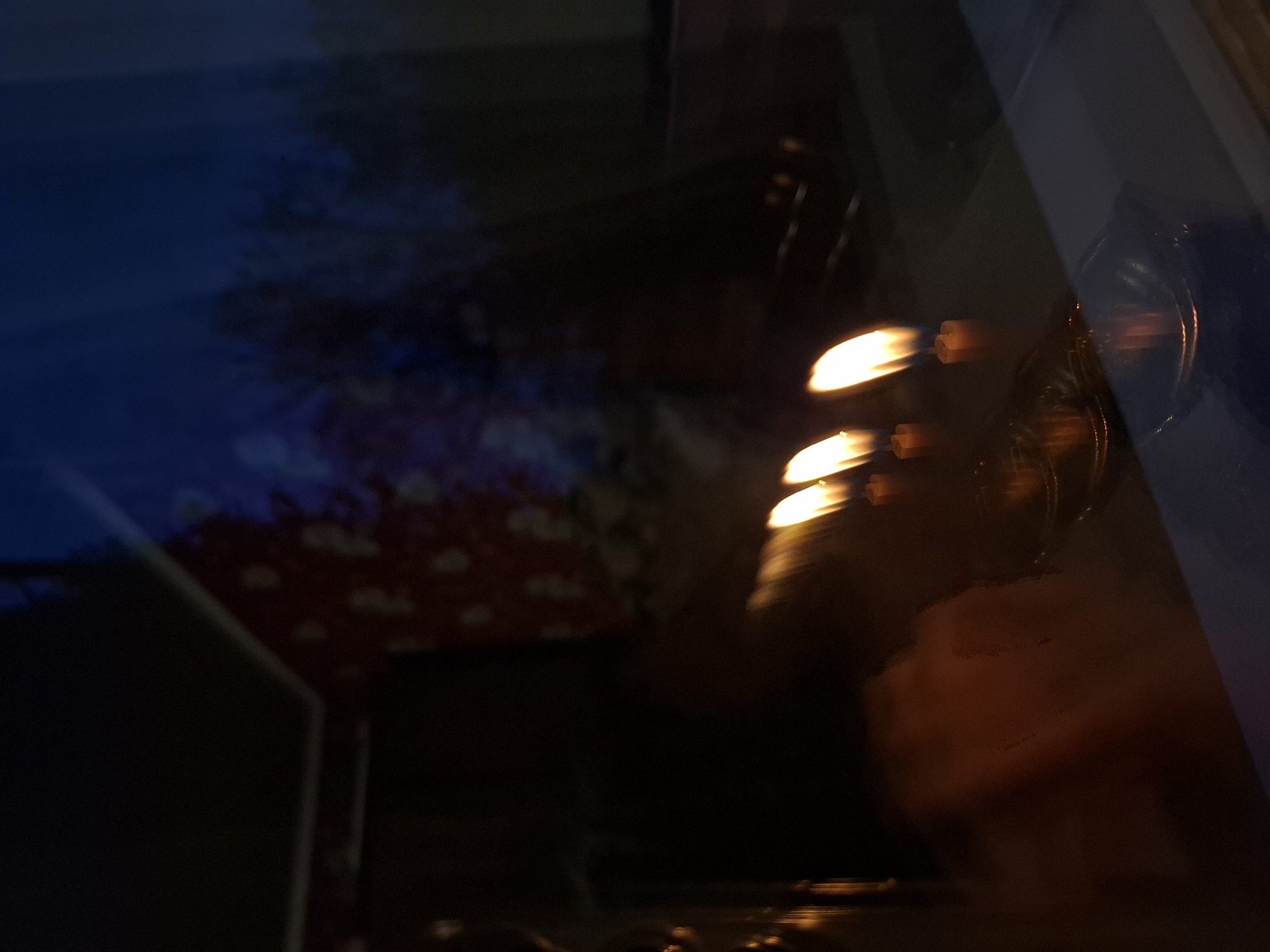 The image is dark and blurry, possibly taken through a reflective surface. There are bright, elongated lights that appear to be reflections. There is a red and white pattern that seems to be reflected or visible through the surface. The location in Khlevnoye, Russia cannot be determined from the image.