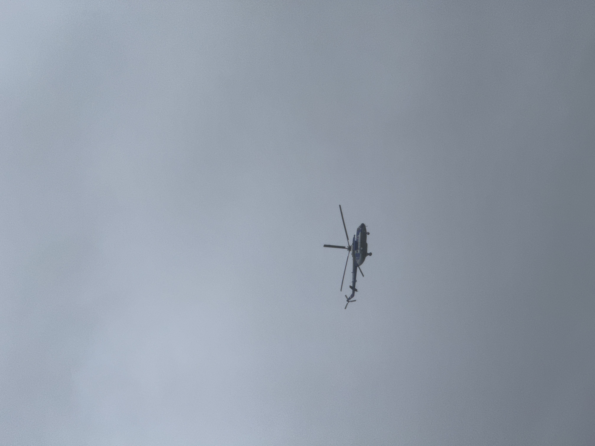 A helicopter is in the sky. The sky is gray. The location is most likely Chaikovsky, Russia, as requested.