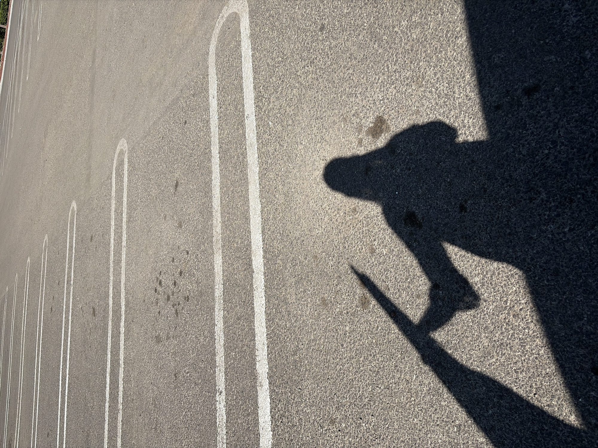An outdoor shot of a concrete parking lot in Puebla, Mexico, shows several parking spaces marked with white U-shaped lines. A dark shadow, possibly cast by a person and a building, is visible on the right side of the image.