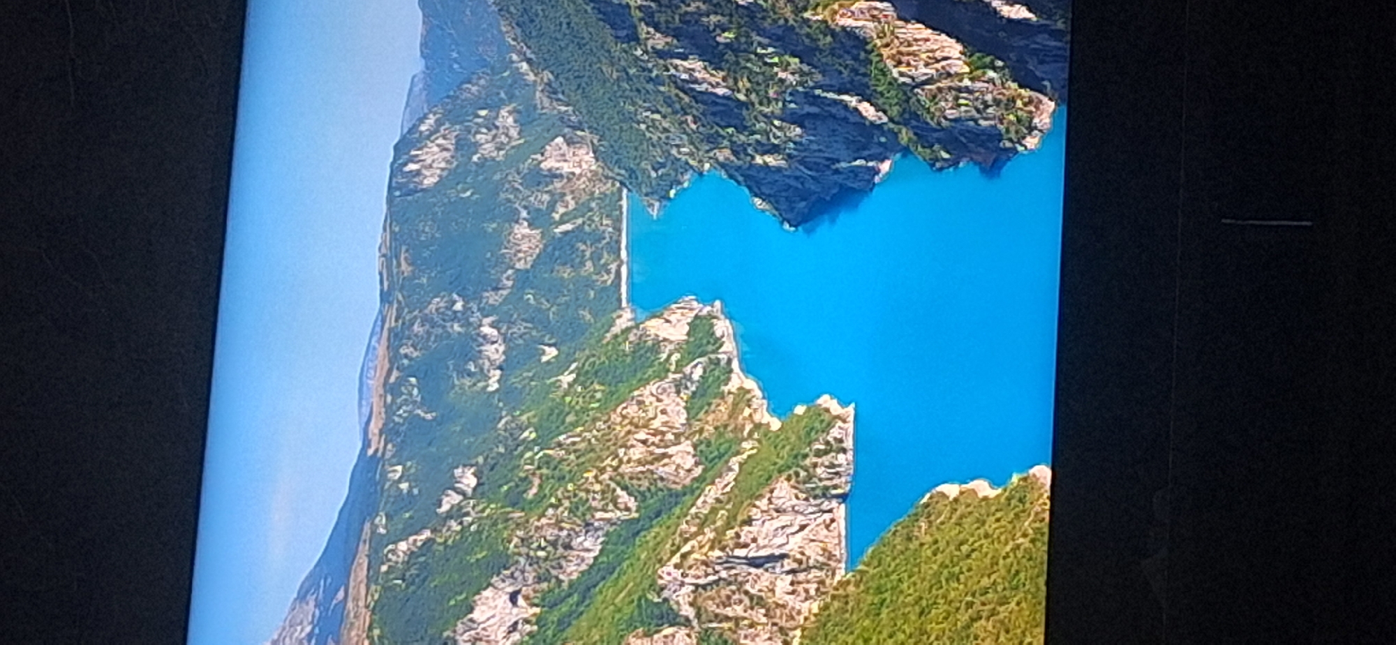 The image shows a panoramic view of a turquoise river winding through a deep gorge. The gorge walls are steep and covered with lush green vegetation and rocky outcrops. The sky above is a clear, bright blue. The scene appears to be a natural landscape, likely a national park or a scenic viewpoint. There are no people or man-made structures visible in the image, suggesting a remote and untouched environment. The photographer appears to be standing at a high vantage point, looking down into the gorge and along the river. The quality of the image suggests it was taken with a camera or smartphone, possibly in daylight. There is no information within the image that places it in Bila Tserkva, Ukraine.