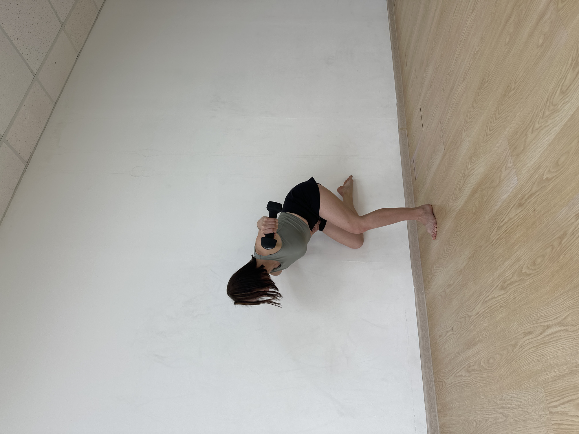 A woman is holding a dumbbell in what appears to be an indoor gym or studio with white walls and a wooden floor. The location in Votkinsk, Russia, cannot be determined from this image.