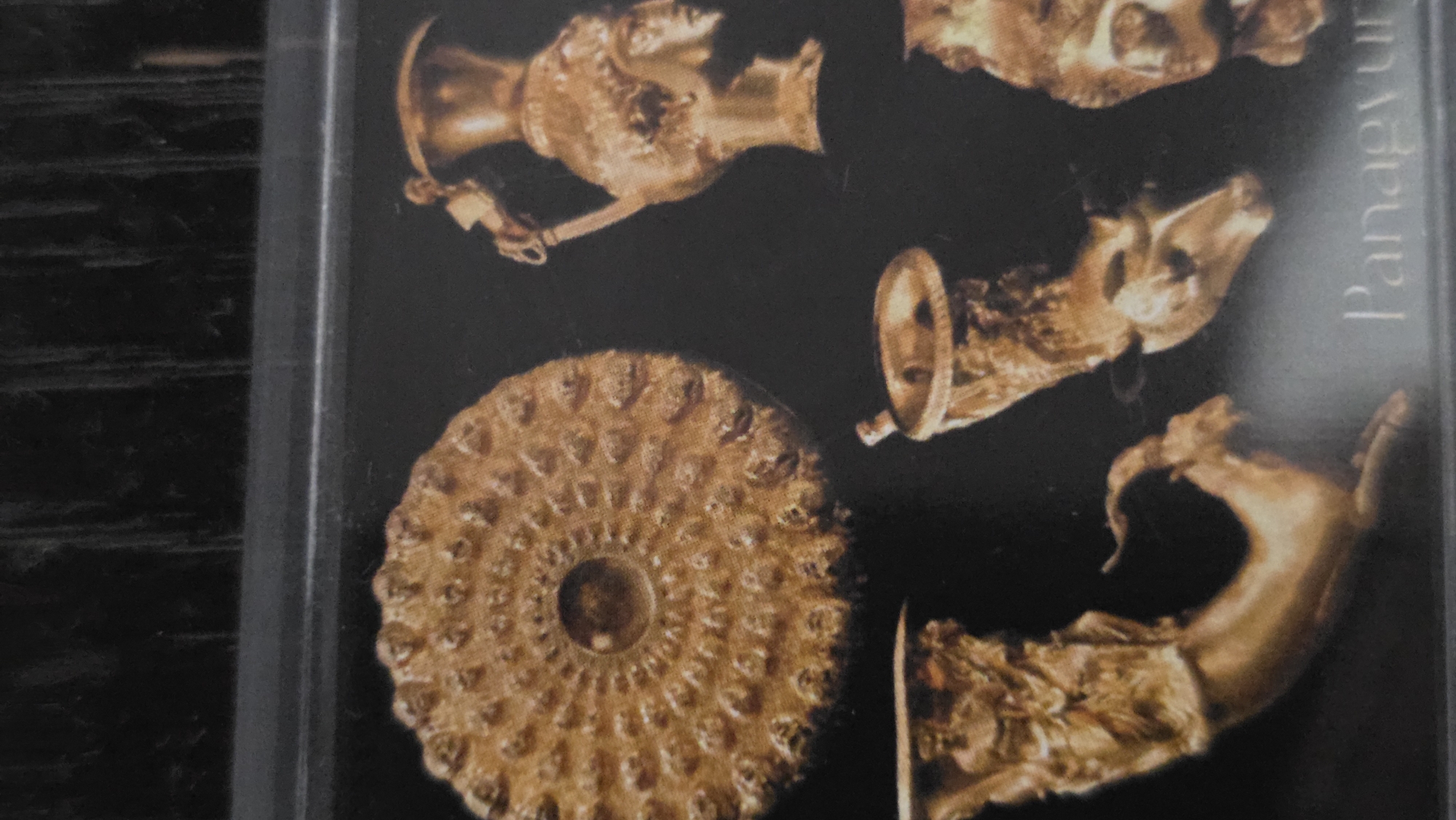 The image shows a photograph of artifacts from the Panagyurishte Treasure. The treasure includes a rhyton (drinking horn) in the shape of an animal head and other golden vessels. The artifacts are displayed against a dark background. The word "Panagyurishte" is partially visible, and the overall appearance suggests a museum display or exhibit. The treasure was discovered in 1949 in Panagyurishte, Bulgaria, not Blagoevgrad.