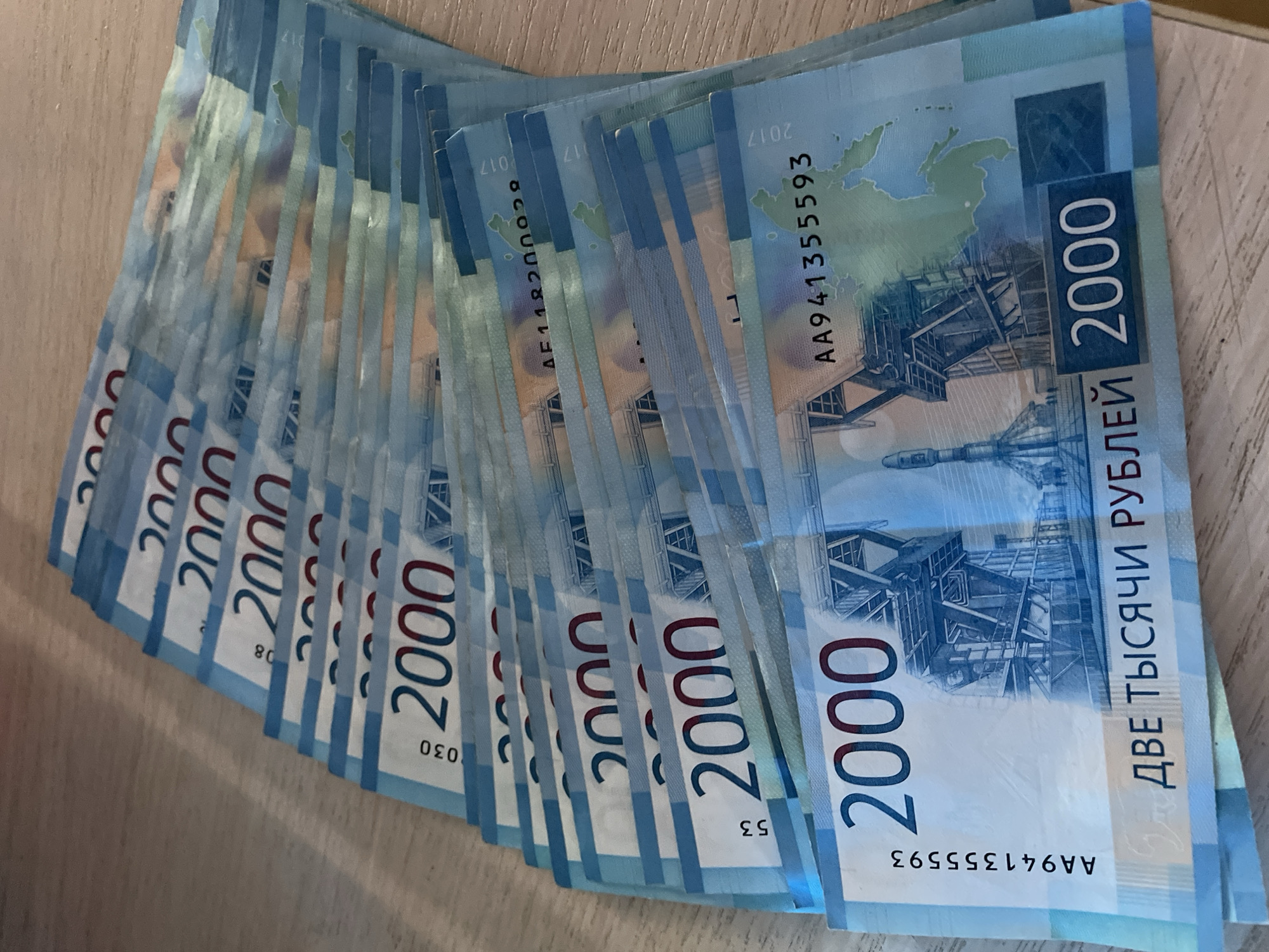 The image shows a fan of 2000 Russian ruble banknotes. The notes are blue and white, and feature images of the Russky Bridge in Vladivostok and a map of Russia. The location of Фоки, Russia is not depicted in the image.