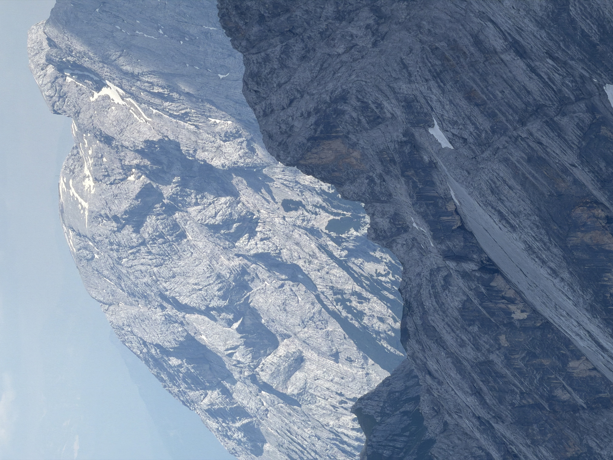 This media file depicts a majestic mountain landscape, likely in Garmisch-Partenkirchen, Germany, characterized by steep, rocky slopes and dramatic geological formations. The primary subjects are the mountains themselves, rendered in shades of grey and blue, with textures that reveal layers of rock and erosion. Patches of snow are visible on the lighter-colored mountain face, suggesting either a high altitude or a recent snowfall. The scene is bathed in natural light, with shadows playing across the rugged surfaces, indicating it is likely daytime. The weather appears clear, with a soft blue sky visible in the background, though the focus remains on the imposing rock faces. There is a strong sense of scale and grandeur, evoking feelings of awe and remoteness. The composition is dominated by the sharp, angular lines of the mountains, with one prominent, darker rock face veiling a significant portion of a lighter, snow-dusted peak behind it. This creates a sense of depth and mystery, hinting at hidden valleys or further mountainous terrain. There is no visible text within the image.