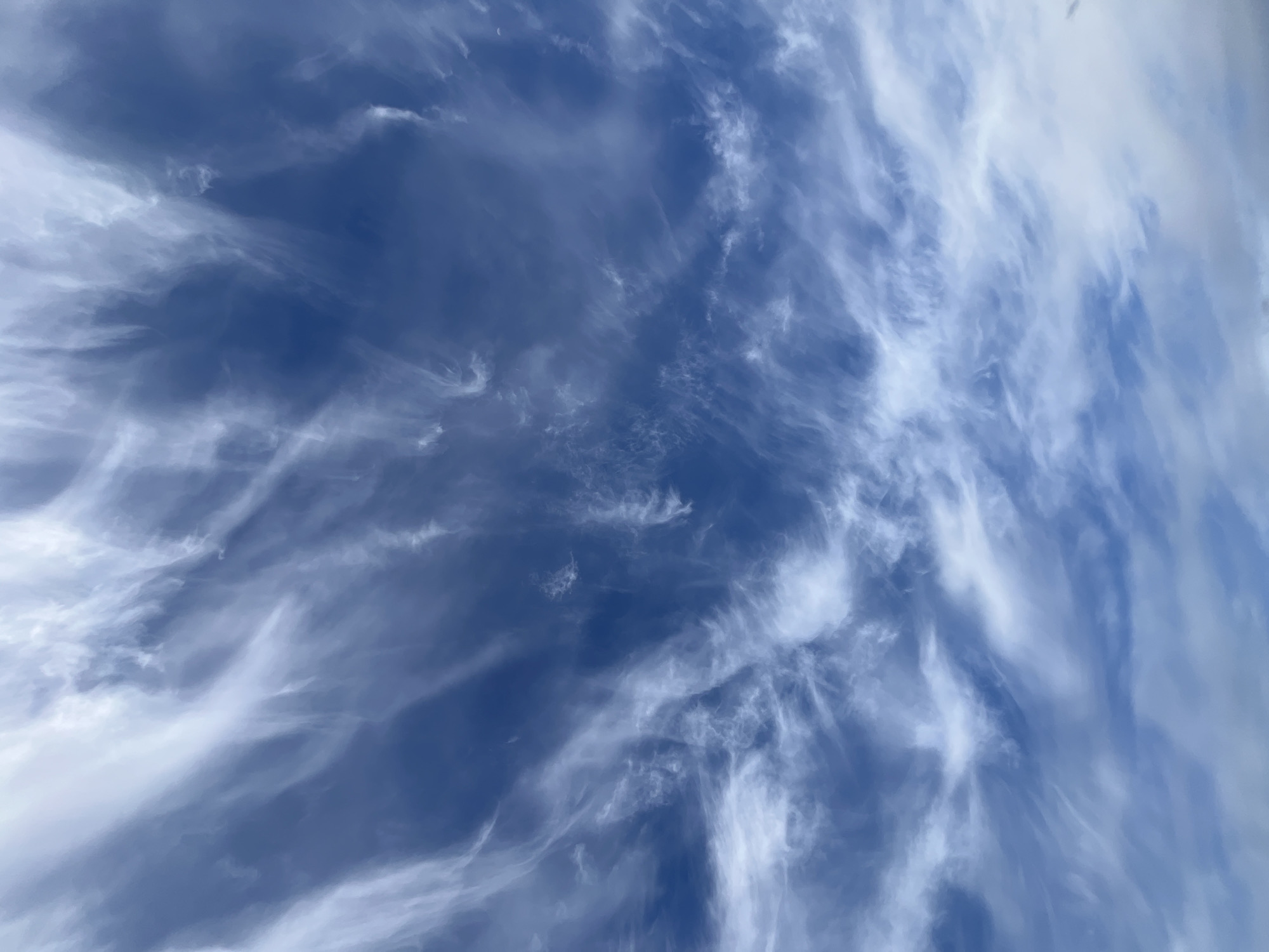 The image shows a blue sky filled with wispy, white cirrus clouds. There is no visible indication of a city or location. It is impossible to ascertain the location of Зыково, Russia from the image. There are no people, subjects, objects, actions, or interactions visible.