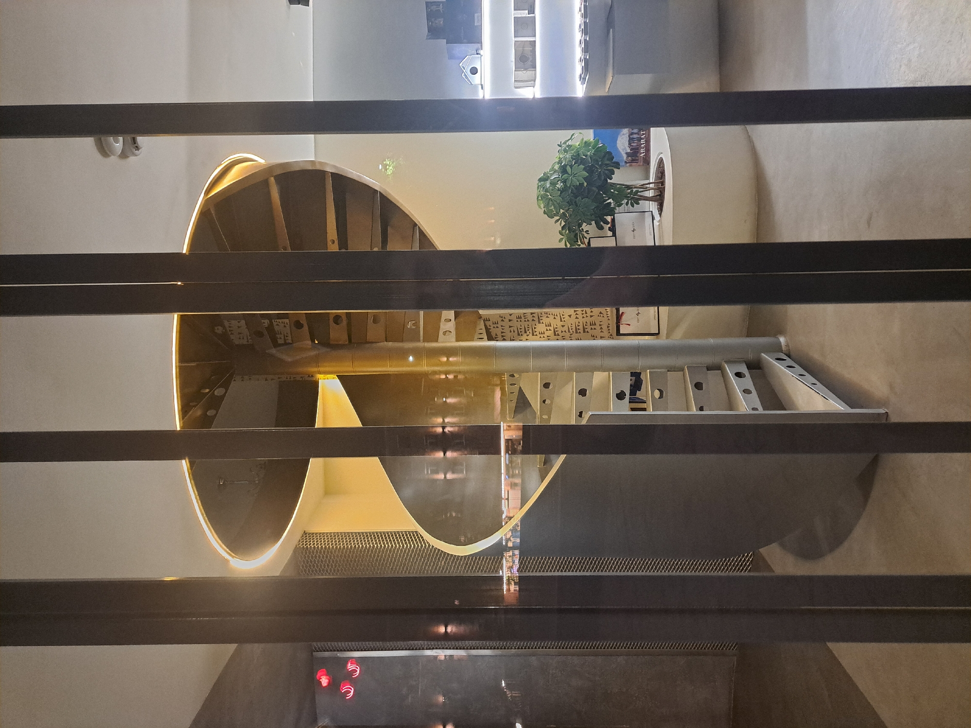 The image depicts an interior space featuring a spiral staircase. The staircase is constructed with a combination of materials, including wood, metal, and potentially concrete. The steps are illuminated with embedded lights, accentuating the curve of the structure. The setting appears to be within a modern, minimalist building, evident from the clean lines and neutral color palette.
The location is not discernible from the image alone and cannot be confirmed as Yerevan, Armenia.