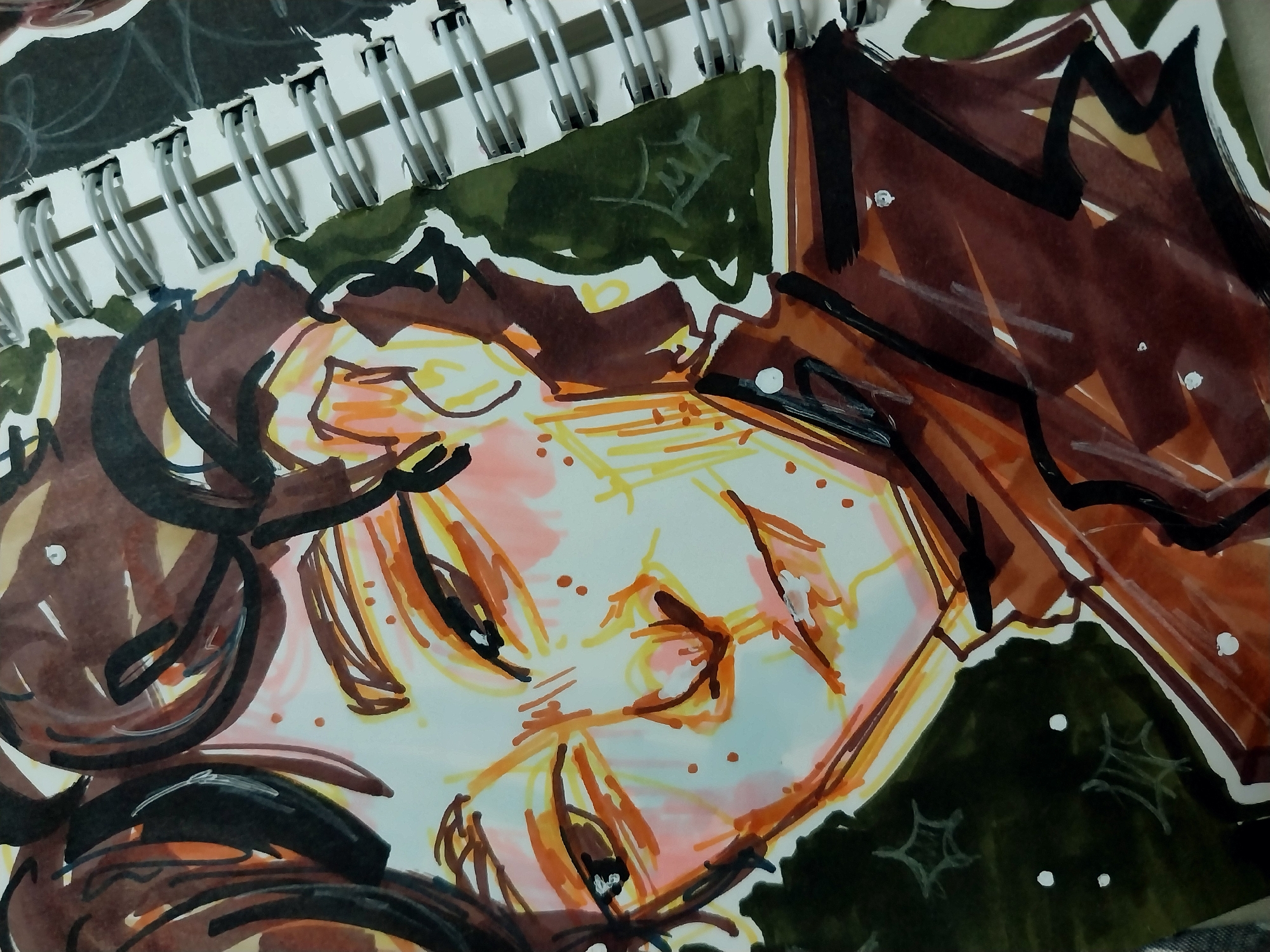 A close-up, high-angle shot shows a sketchbook open to a drawing of a person's face. The drawing is done in markers with brown, orange, yellow, and pink tones, with black ink outlines. The subject's eyes are looking to the left, and they have a slight smile. There are freckles on their nose and cheeks. The drawing is unfinished, with some areas filled in with color and others left as sketches. The spiral binding of the sketchbook is visible on the right side of the image, along with a bit of the next page. The background is dark green, with white dots and star-like shapes scattered across it. The drawing is on a white page within the sketchbook.