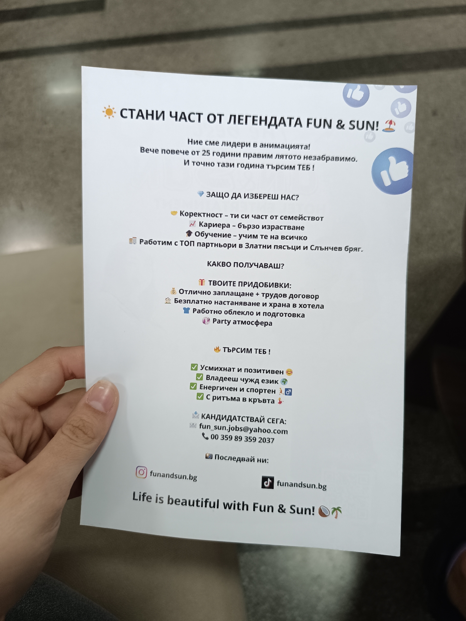 A person is holding a flyer with the text "СТАНИ ЧАСТ ОТ ЛЕГЕНДАТА FUN & SUN!" which translates to "BECOME A PART OF THE LEGEND FUN & SUN!". The flyer is an advertisement for job opportunities at Fun & Sun, highlighting benefits such as good pay, free accommodation and food, training, and a party atmosphere. It also lists requirements such as being smiling and positive, speaking a foreign language, being energetic and sporty, and having rhythm. The flyer includes contact information and social media handles.