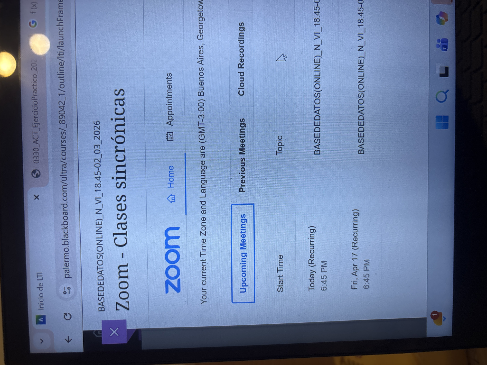 The image shows a screenshot of a Zoom meeting schedule accessed through a web browser. The website is identified as belonging to "palermo.blackboard.com," suggesting it's related to an educational institution. The meeting is titled "BASEDEDATOS(ONLINE)_N_VI_18.45-02_03_2026 - Clases sincrónicas" (which translates to "Online Database - Synchronous Classes"). The schedule indicates upcoming meetings today at 6:45 PM and on Friday, April 17, also at 6:45 PM. The time zone is specified as (GMT-3:00) Buenos Aires, Georgetown. This means the user is located in a region observing Argentina Time.