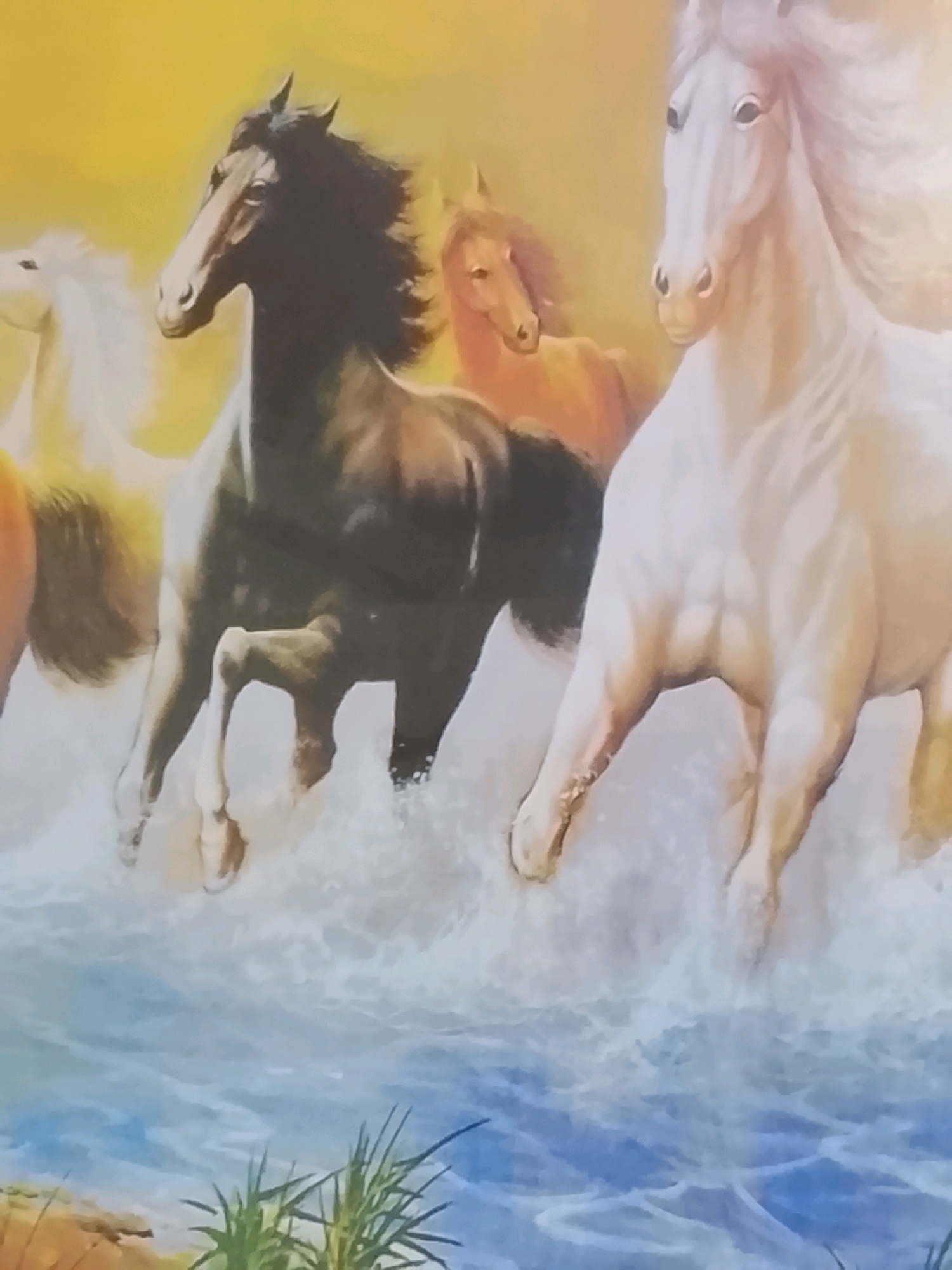 The image depicts a painting of four horses running through water. The horses are of various colors, including white, black, and brown. The foreground shows water with splashes and foam, indicating motion. The background is a gradient of yellow, suggesting a bright, possibly sunny, environment. There are no people visible in the image, and the scene is entirely composed of the painted horses and their surroundings. There is no information within the image itself that would associate it with Kalibeji, Indonesia.