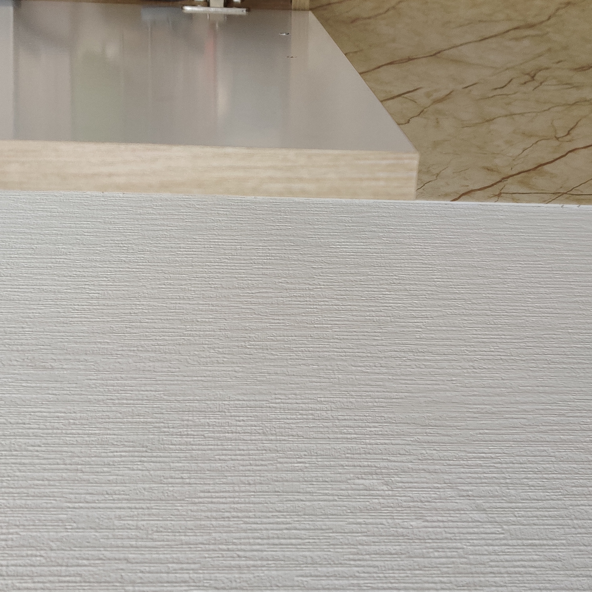 The image displays a close-up, eye-level, interior shot of a wall with a textured, vertical pattern. To the right of this textured wall, there is a narrow vertical section of light wood grain, followed by a frosted glass panel. Further to the right, a section of marble-patterned surface is visible, angled upwards. The scene is devoid of people or any discernible activity. The lighting is neutral, and the overall impression is of architectural or decorative elements. There is no information in the image to suggest a specific location in Yekaterinburg, Russia.