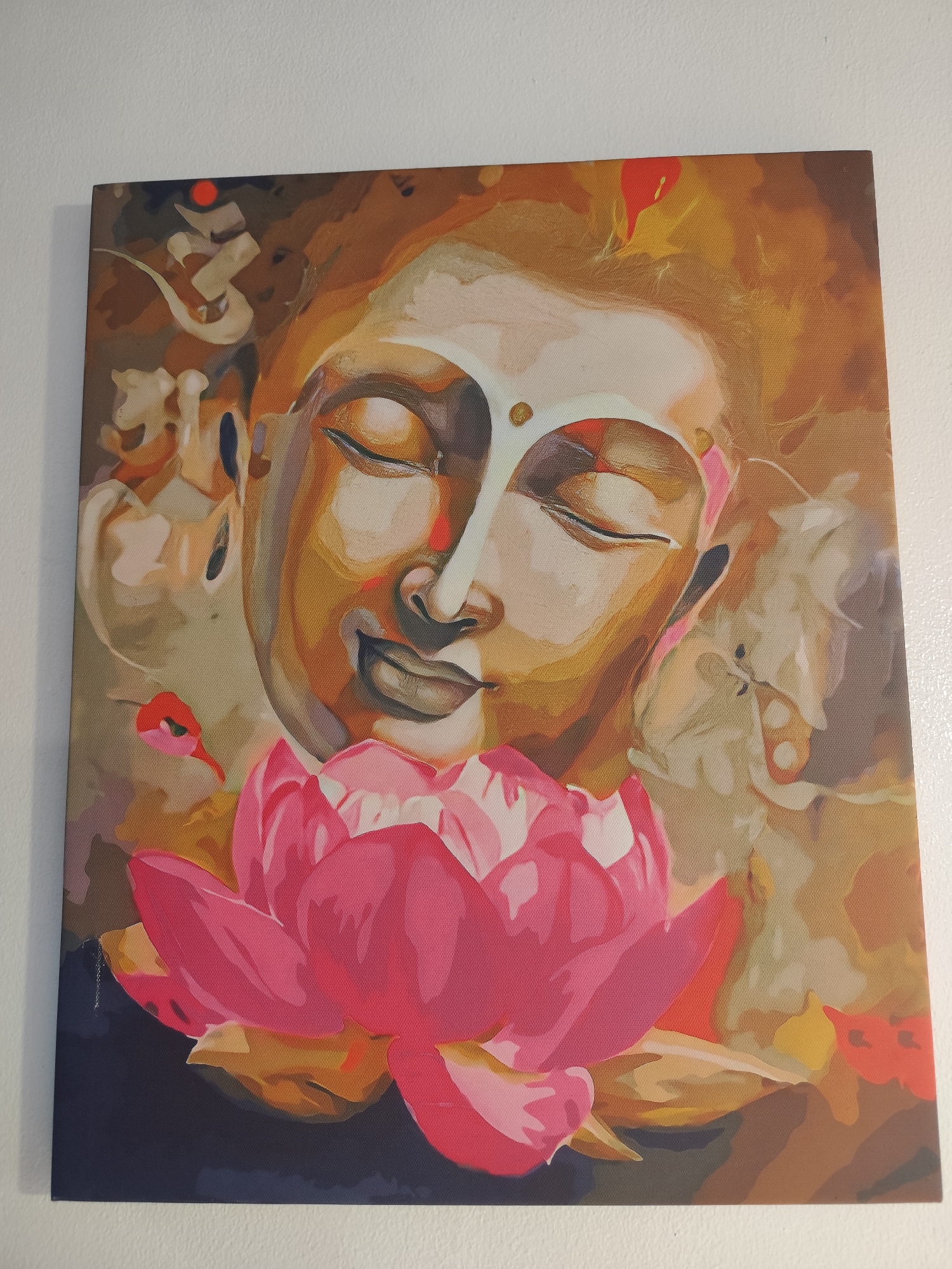 The image shows a painting of Buddha with a lotus flower in the foreground. The painting is mostly in shades of brown, beige, and pink. The background is abstract and indistinct. The lotus flower is large and pink, with some yellow and orange highlights. The painting is mounted on a white wall. Da Lat, Vietnam is not represented in this image.
