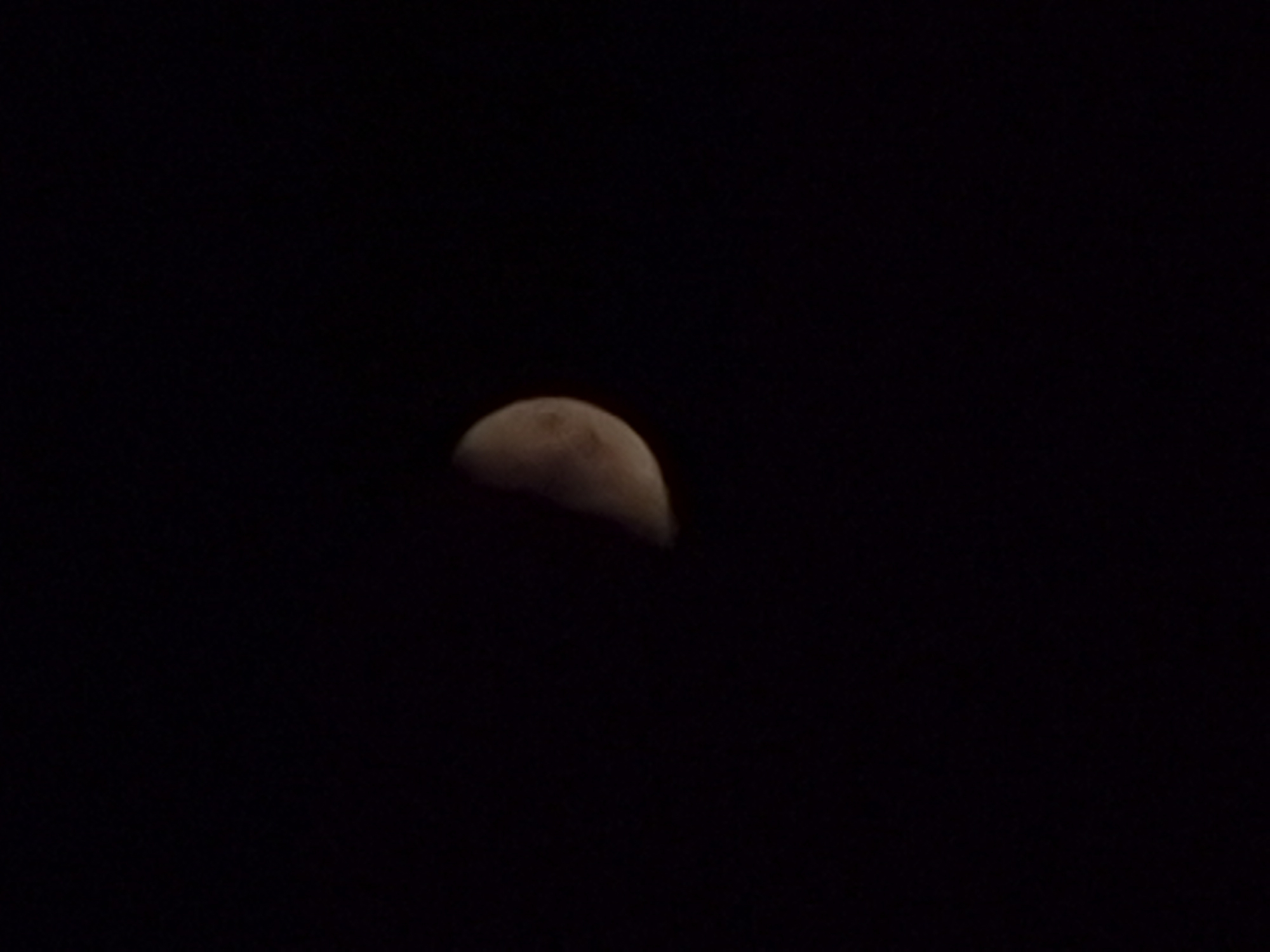 The image shows a partial view of the moon against a dark sky. The moon is illuminated on its right side, appearing as a crescent. The surrounding area is black, indicating a night scene with no other visible celestial bodies or artificial lights. The image does not contain any information or context related to the city of Pernik, Bulgaria.