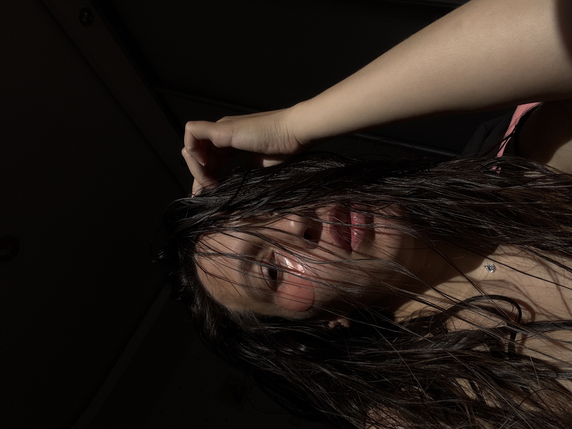 A close-up, low-angle shot depicts a person with wet, dark hair obscuring their face. The person's right hand is resting on their forehead. Their face is illuminated in stark contrast to the dark background. The location and presence of Chaikovsky, Russia cannot be determined from the image.