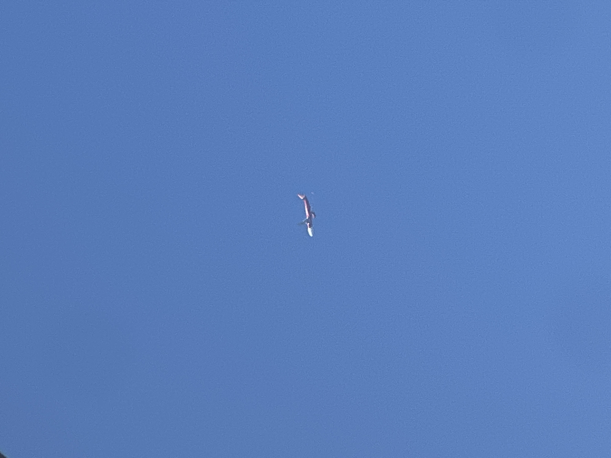 An airplane is flying in the sky. The background is a solid, light blue color.
The plane's fuselage is reddish-purple. The wings appear to be white or light colored.
The scene appears to be in the daytime, based on the sky's color and lack of shadows.
This information is insufficient to confirm the location as Nam Nha Trang Ward, Vietnam, as the image only shows the sky and airplane.