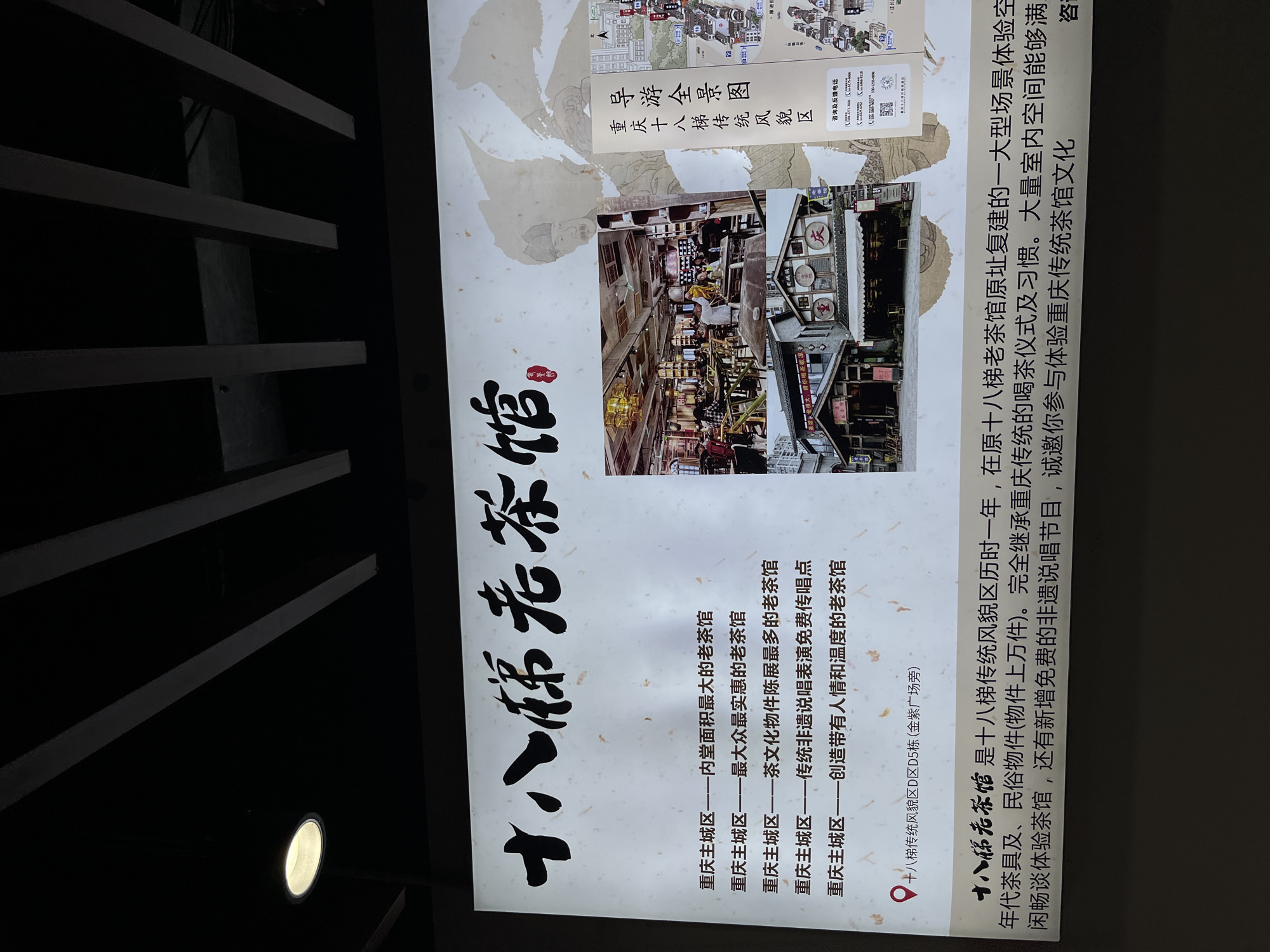The image shows a sign for the "Eighteen Ladders Old Teahouse" (十八梯老茶馆) located in the Yuzhong District (渝中区) of Chongqing, China. The sign lists characteristics of the teahouse: it has the largest indoor area, it is the most affordable, it exhibits the most tea culture artifacts, it offers free traditional intangible cultural heritage (非遗) performance, and it creates a warm and welcoming atmosphere. The sign includes a map of the Eighteen Ladders Traditional Appearance Area (十八梯传统风貌区), specifically building D5 of area D, next to the Jinzi Square (金紫广场旁). A photograph of the tea house's interior decorates the sign. The text explains that the teahouse was rebuilt on the original site, recreating a large scene for visitors to experience traditional Chongqing tea culture. It houses historical tea sets and folk items, and the free performances of intangible cultural heritage increase its cultural appeal.