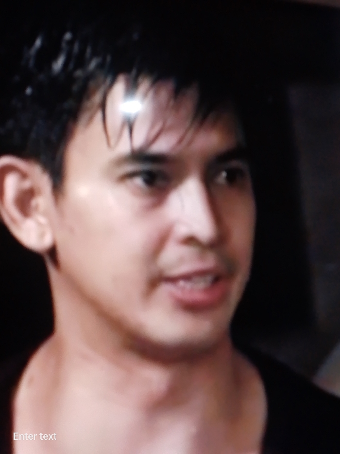 A close-up shot of a man with dark hair and fair skin. He is looking slightly to his right. He is wearing a dark shirt. The location is unknown.