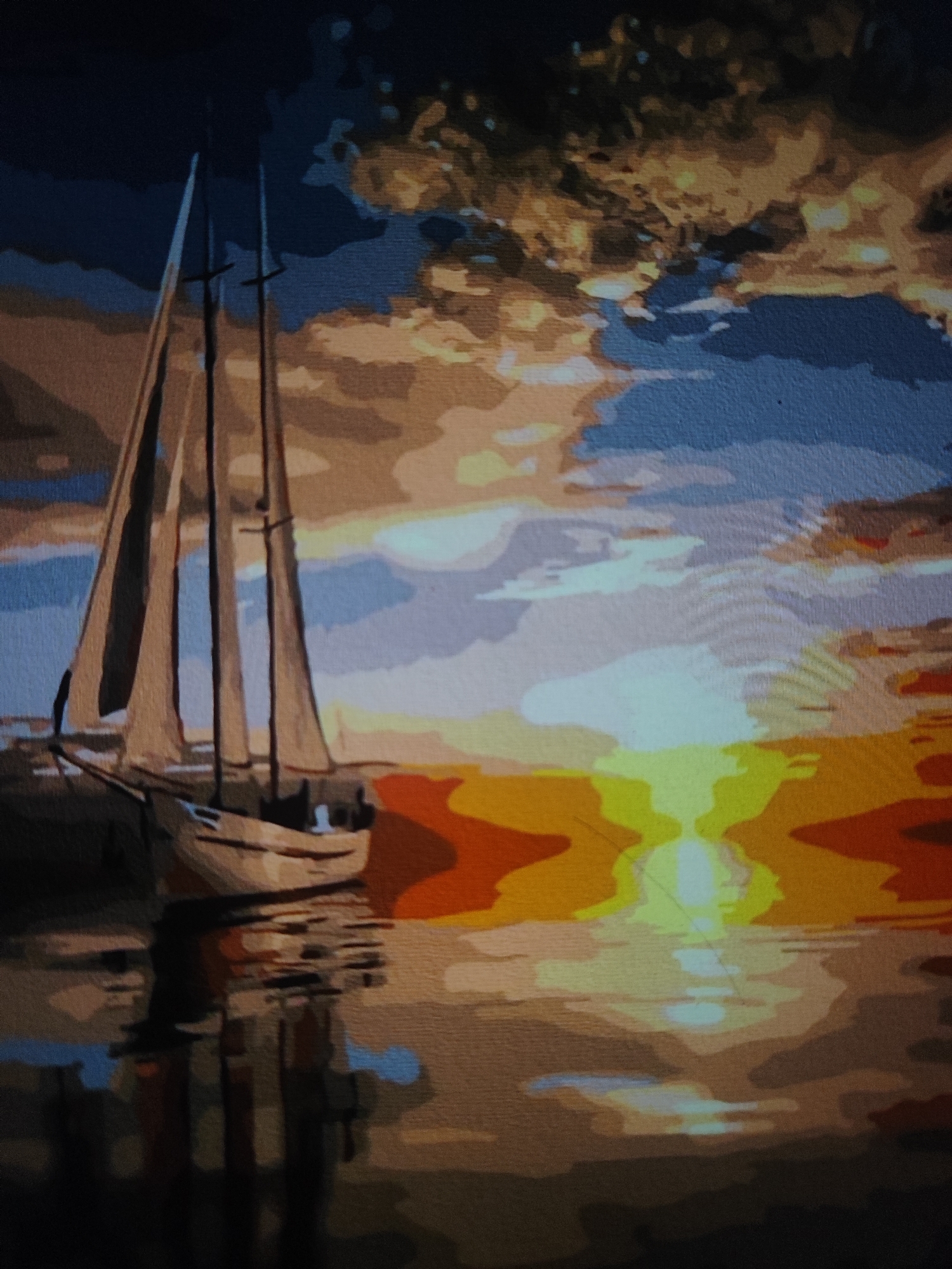The image depicts a painting of a sailboat at sunset on the water. The sky is filled with dramatic clouds in shades of orange, yellow, blue, and dark gray, illuminated by the setting sun. The sun's reflection creates a bright, shimmering path on the water, which is rendered in abstract shapes of orange, yellow, and blue. The sailboat, positioned on the left side of the image, has three sails and is depicted with simple lines and shading. Its reflection is visible on the water, distorted by the ripples. The overall style of the painting is impressionistic, with bold brushstrokes and a vibrant color palette. There is no indication of Fergana City, Uzbekistan, or any urban elements present in the image.