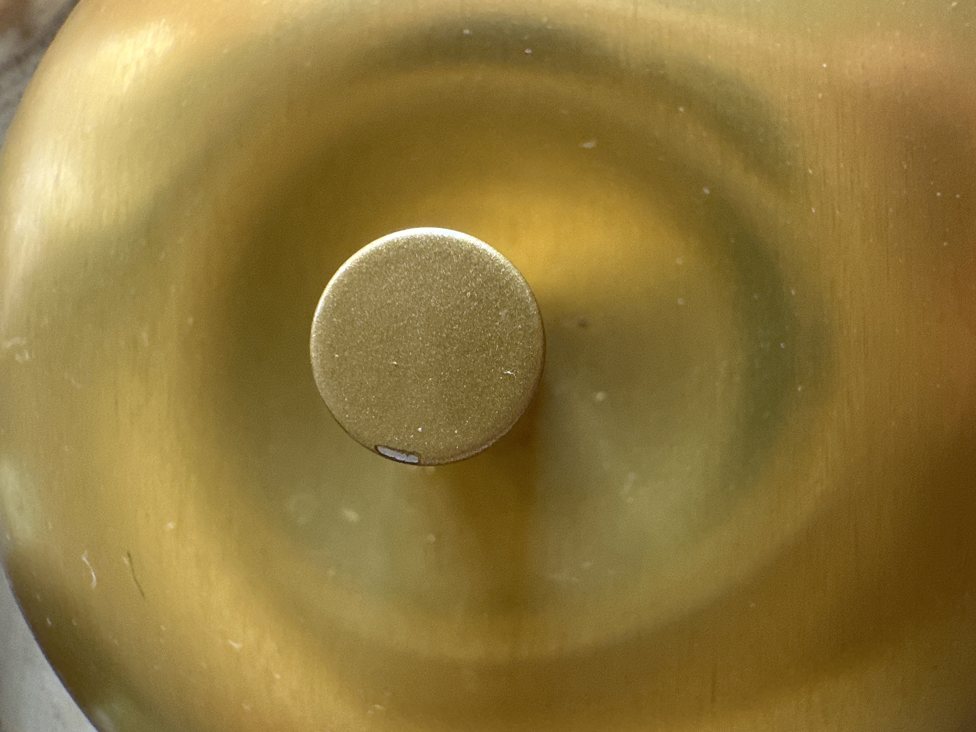 A close-up shot of a gold-colored object, possibly a bell or similar rounded item, is presented. A smaller, round, gold-colored protrusion is centered on the larger object. The surface of both items shows some wear and slight imperfections. The location and presence of people, actions, and interactions are not discernible from this image. No information indicates the scene is located in Petah Tikva, Israel.