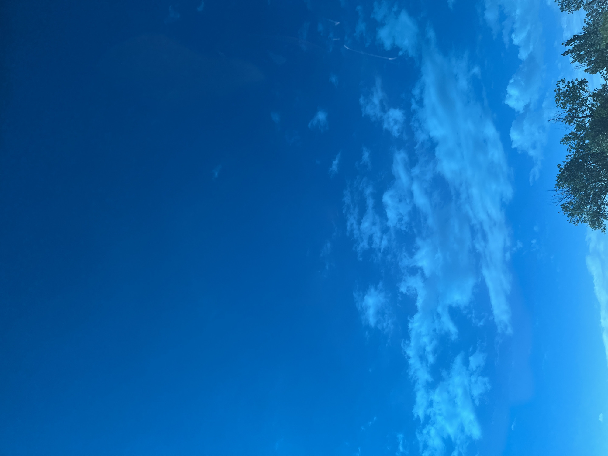 The image depicts a sky with varying shades of blue, with sparse clouds and a small amount of tree cover in the upper right corner. Location information for Tlustenkhabl, Russia, is not available.
